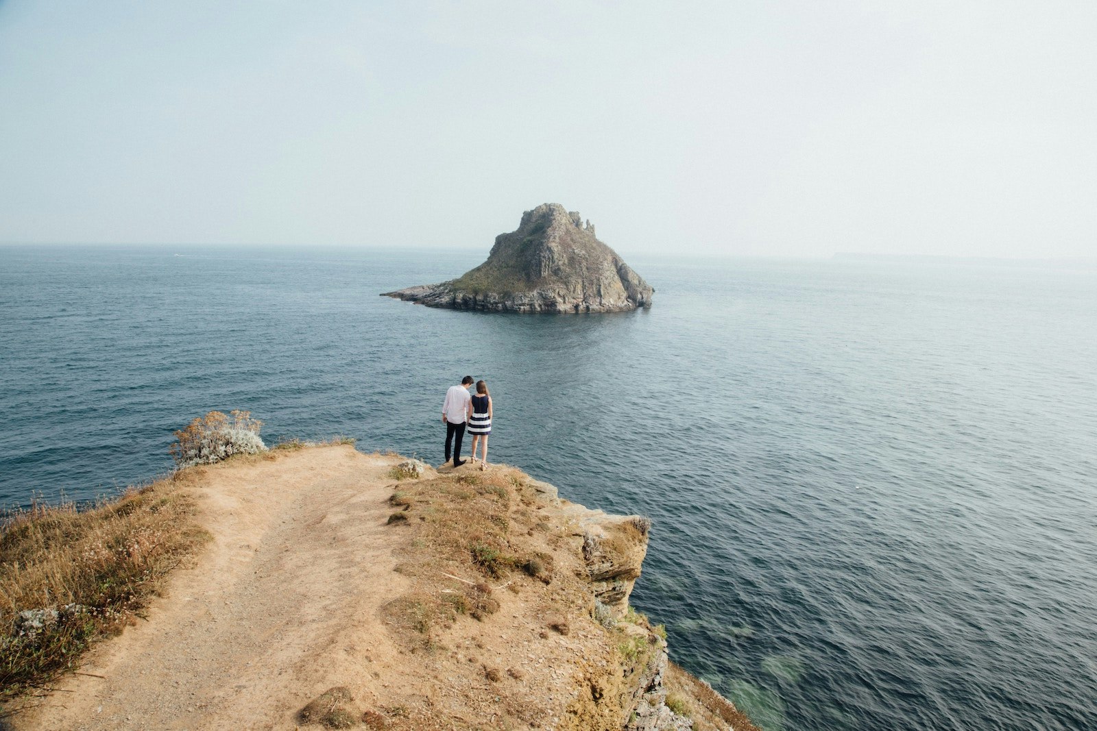 Picture of a couple standing together on a cliff overlooking the ocean