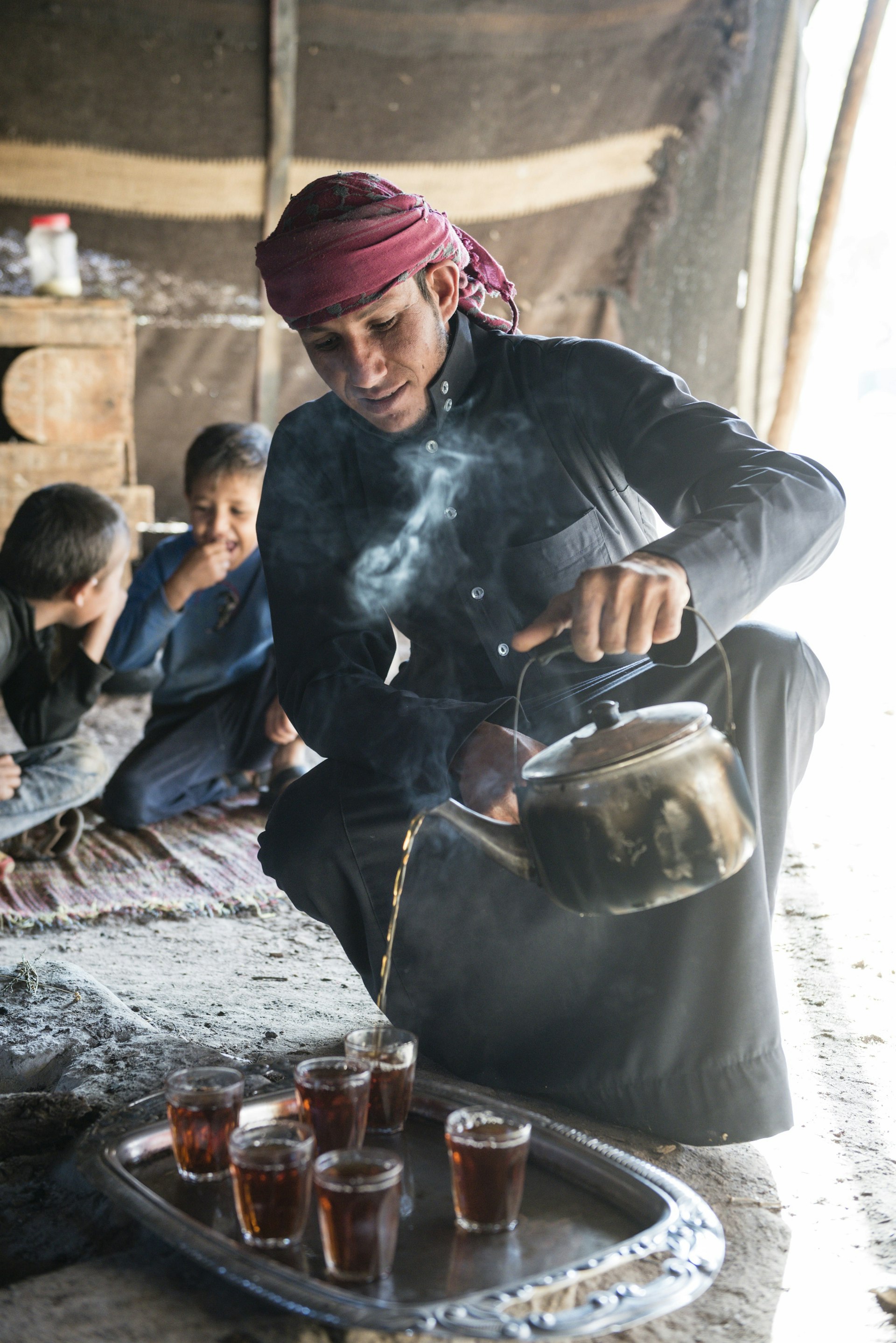 A member of the Beni Atieh tribe pours out tea for guests in a desert tent.