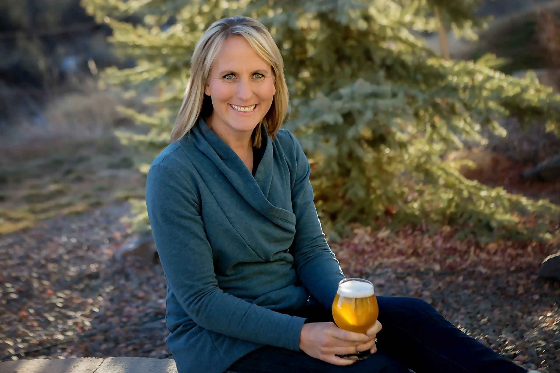 A woman sits outside holding a golden beer