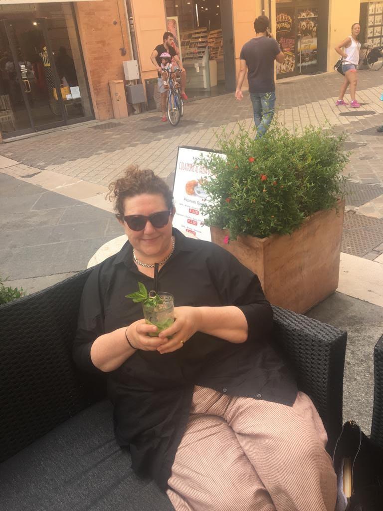 Food critic Katy McGuinness drinks a cocktail while sitting on a bench