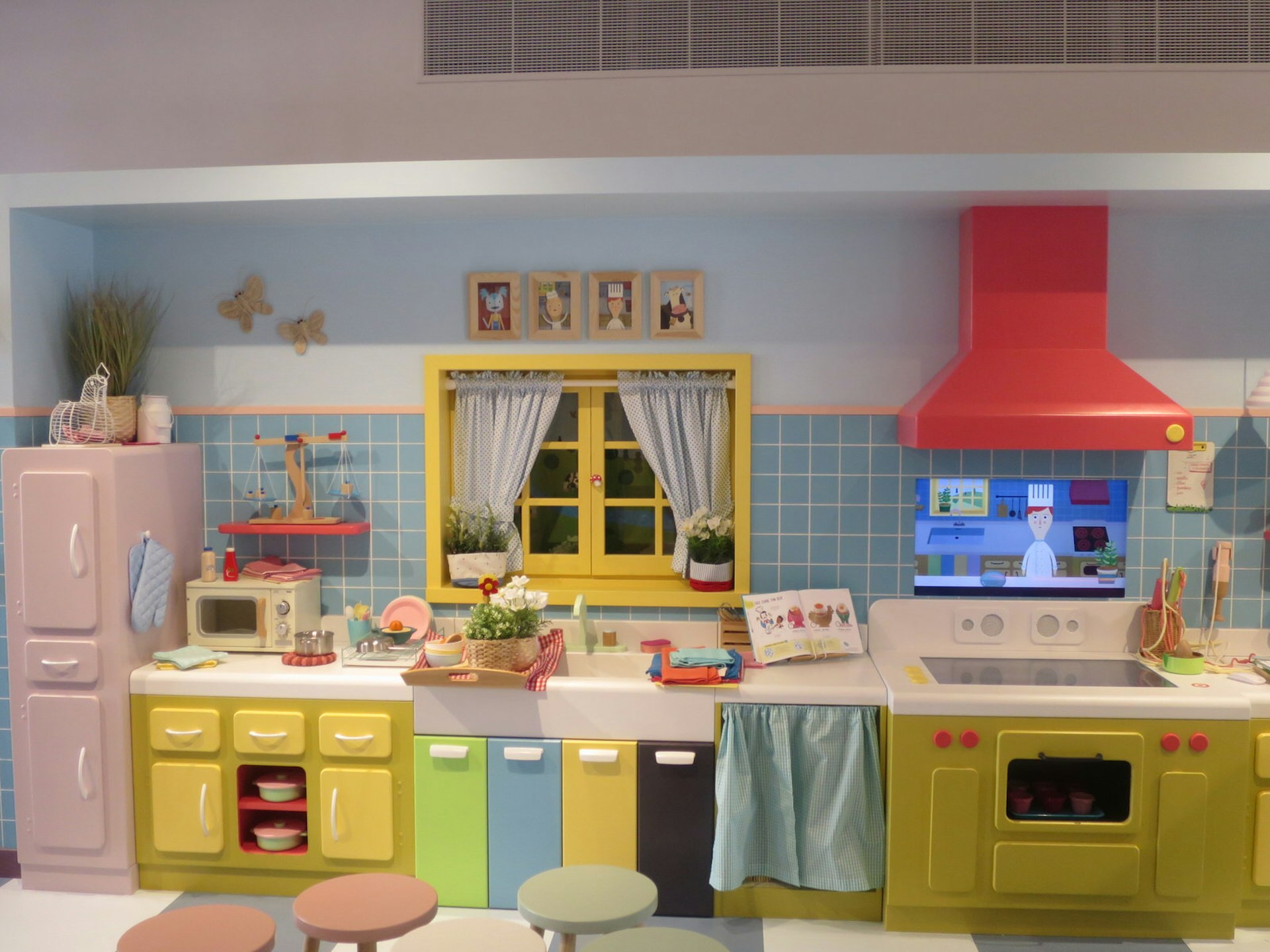 A colourful child-sized kitchen with an interactive screen to teach visitors how to make classic french dishes. 