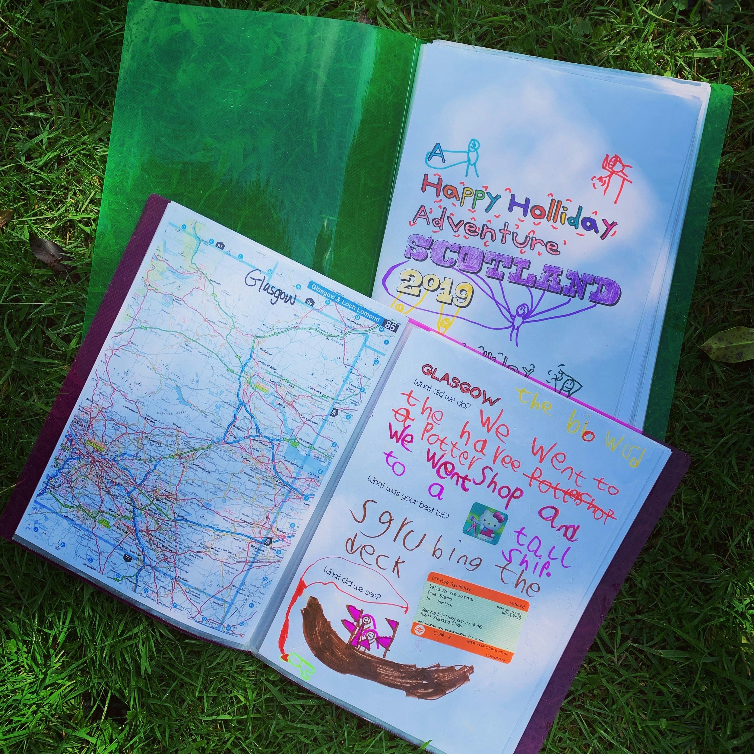 Two notebooks covered in colourful writing, and a map of Glasgow.