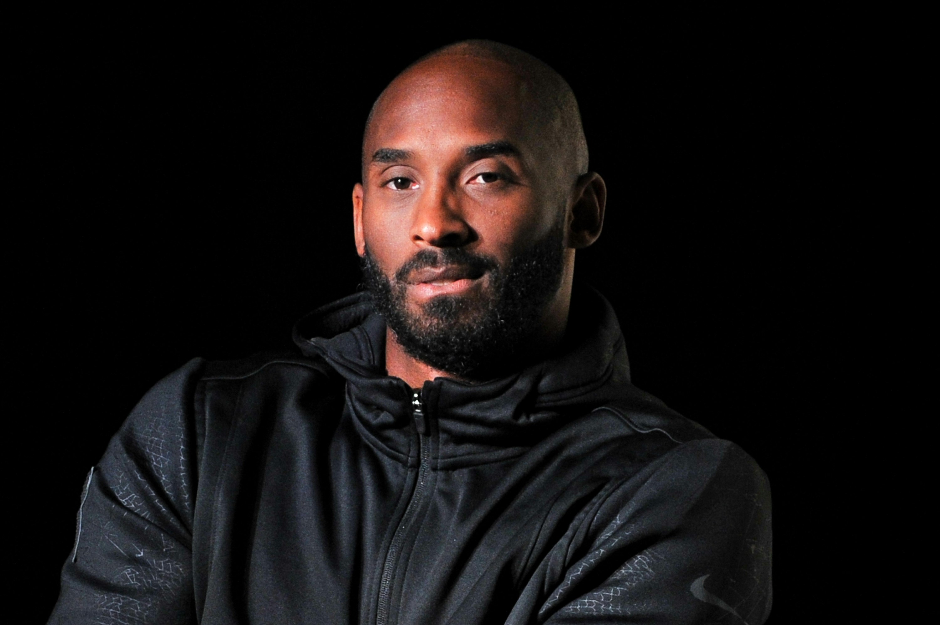 Kobe Bryant is front of a black screen. 