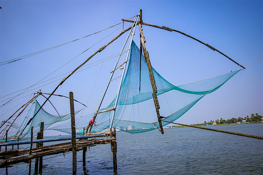 kochi4_KerryWalker-17c5412faed7.jpg A fisherman in a red shirt operates the large, levered fishing nets of Kochi, India.