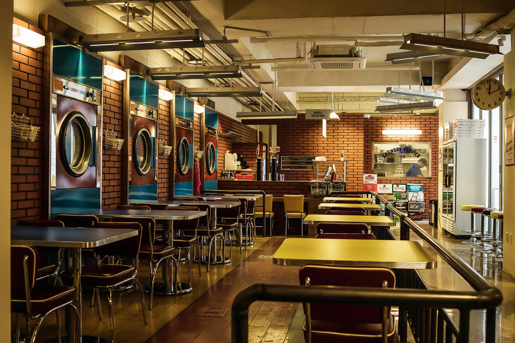 The inside of the Laundry Pizza restaurant in Gangnam, Seoul, with washing machines lining the exposed redbrick walls.