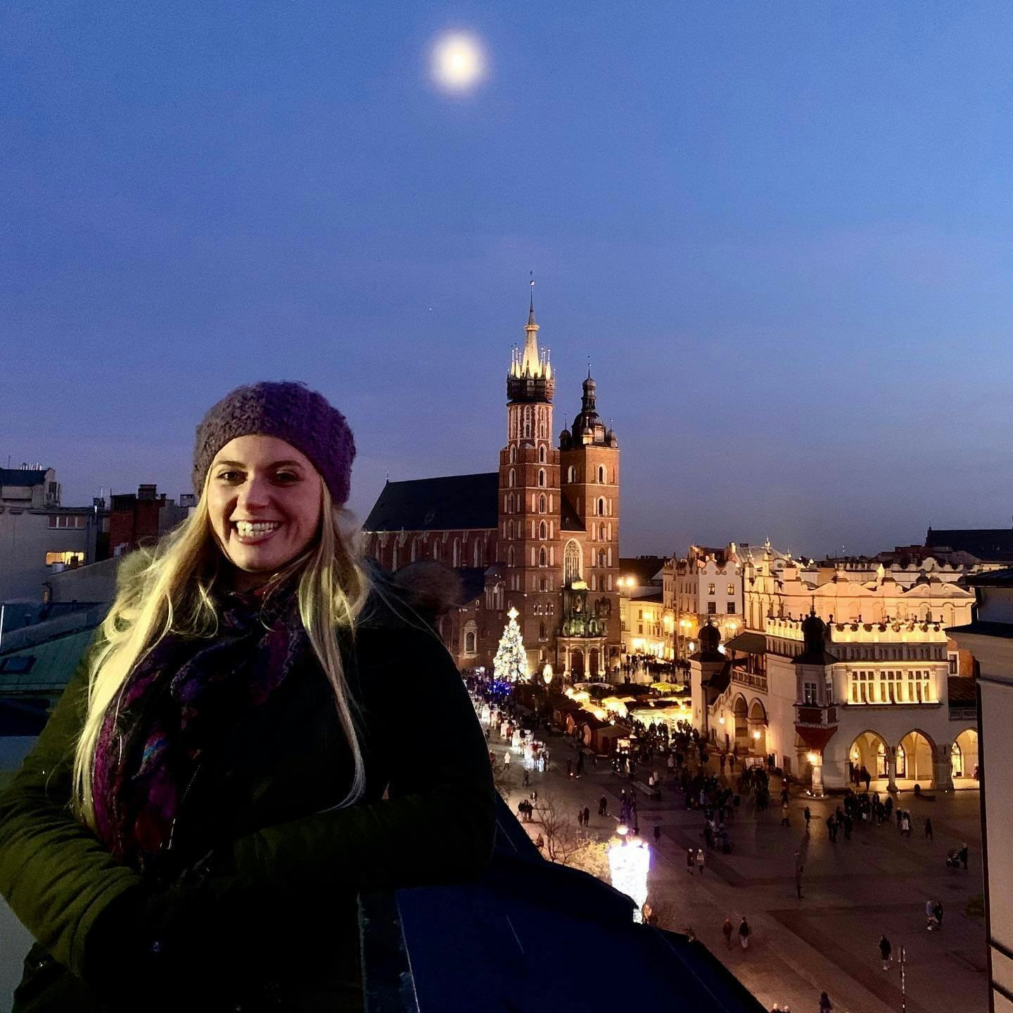 The author smiles in front of an illumianted Wawel Cathedral at night