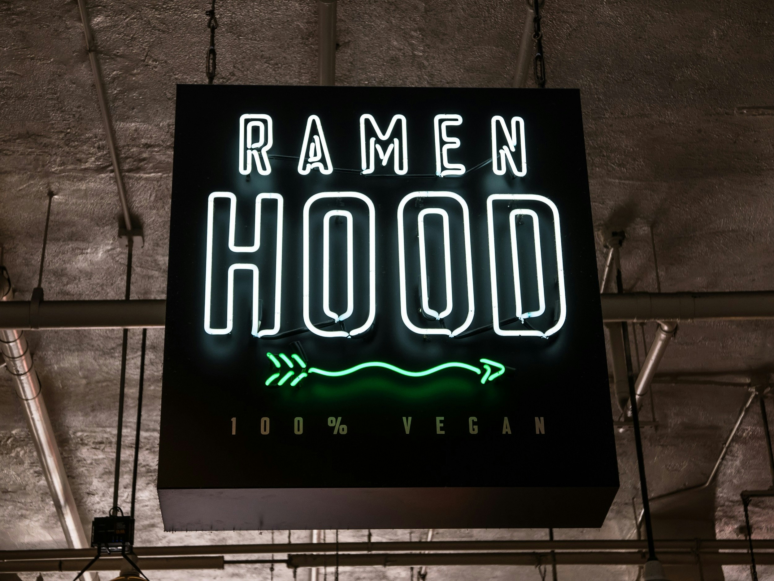 A neon sign for Ramen Hood, 100% Vegan restaurant, hangs outside the premises.