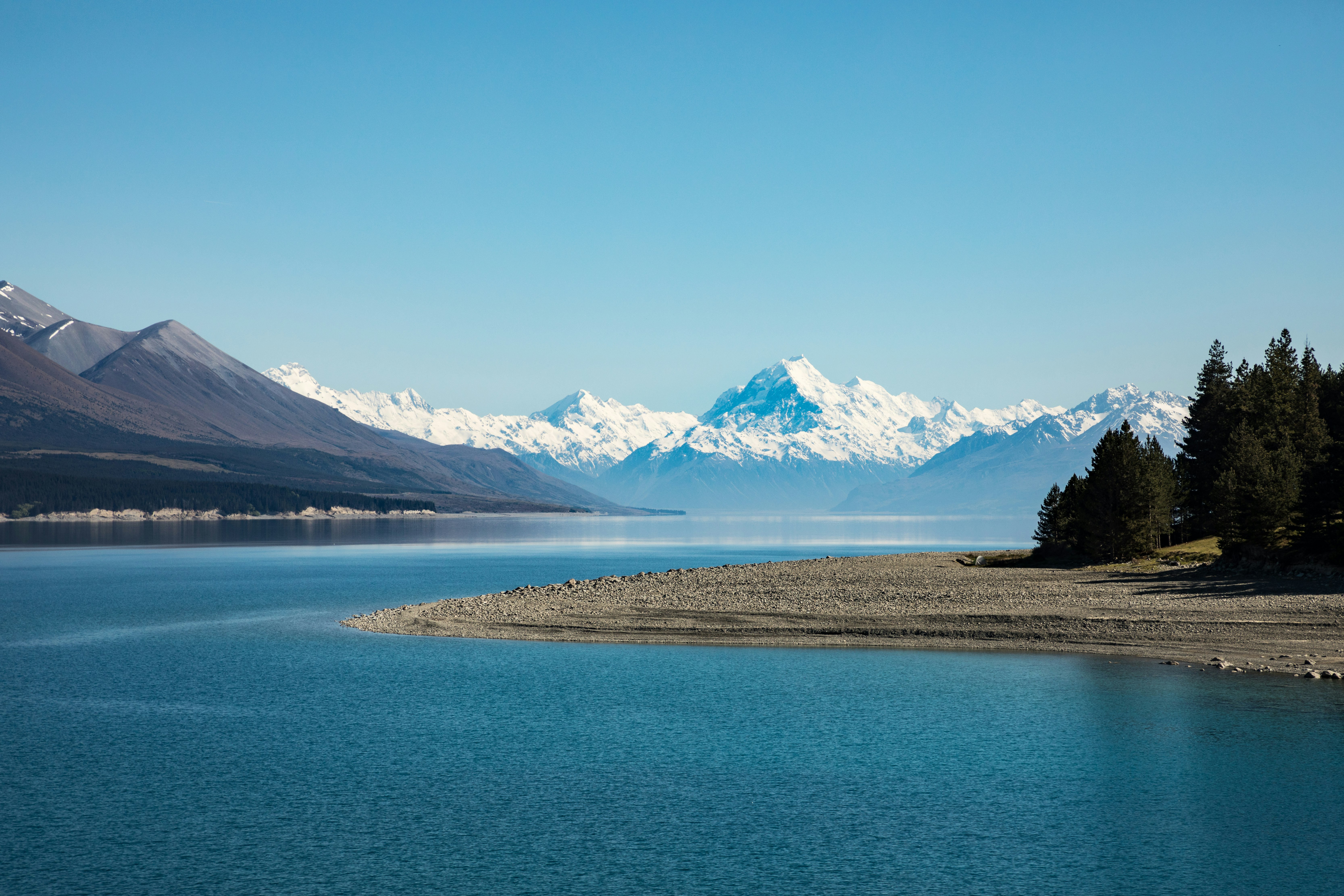 Snow-capped mountains stand in the distance behind Lake Taupō, New Zealand