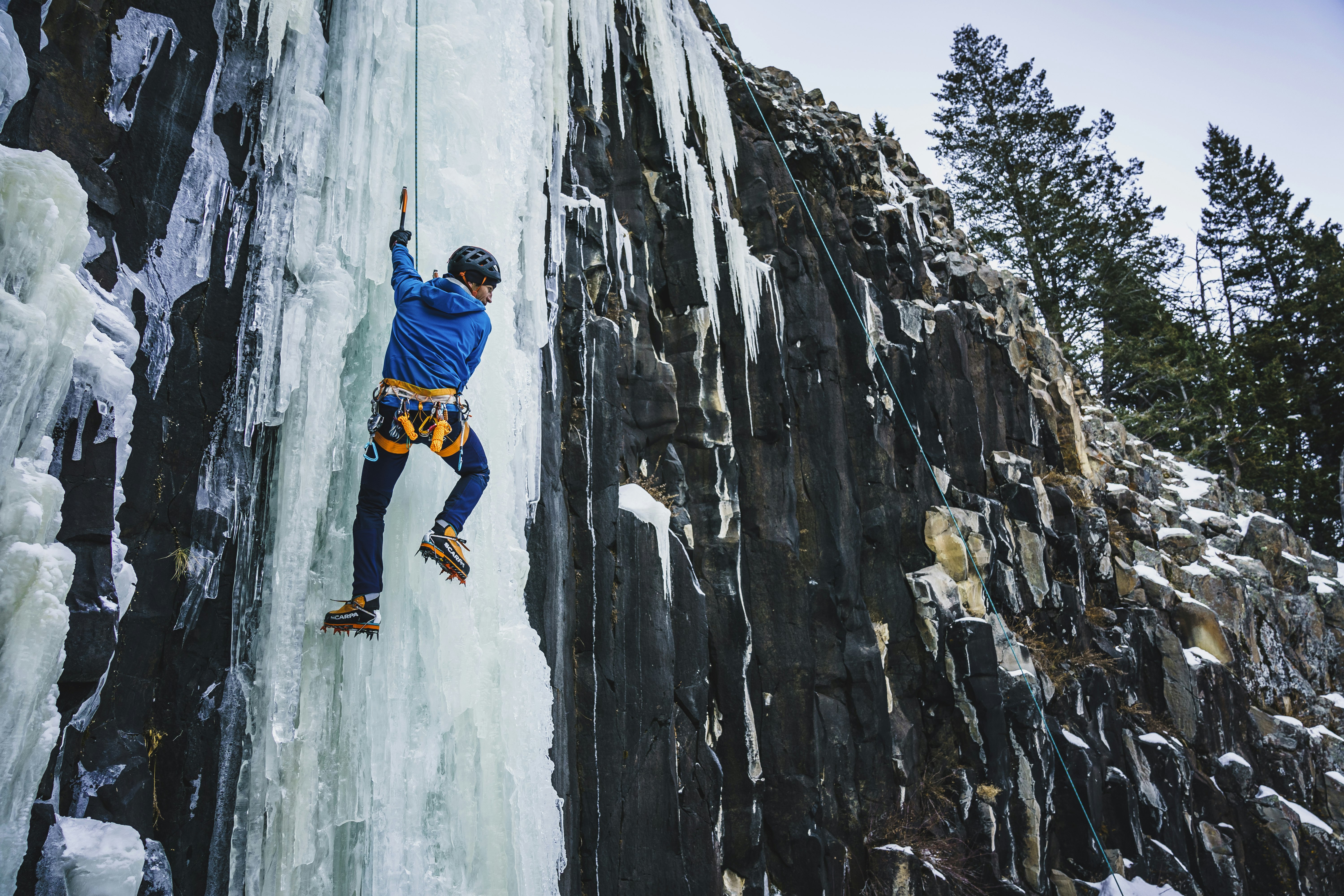 a man uses an axe to climb a wall of ice 