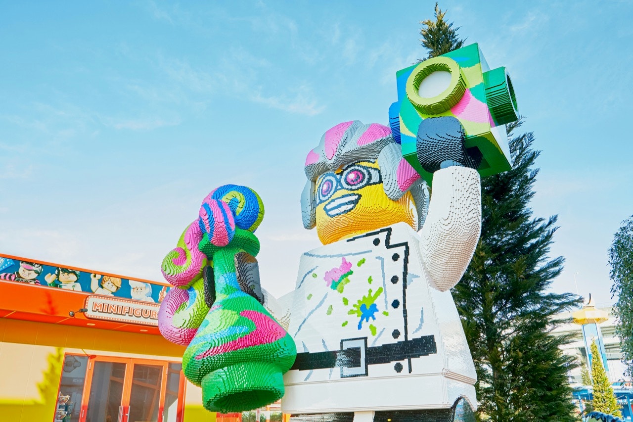 Legoland New York Bricktopia entrance featuring Lego man with pink and grey hair holding multicolor block and overflowing potion bottle