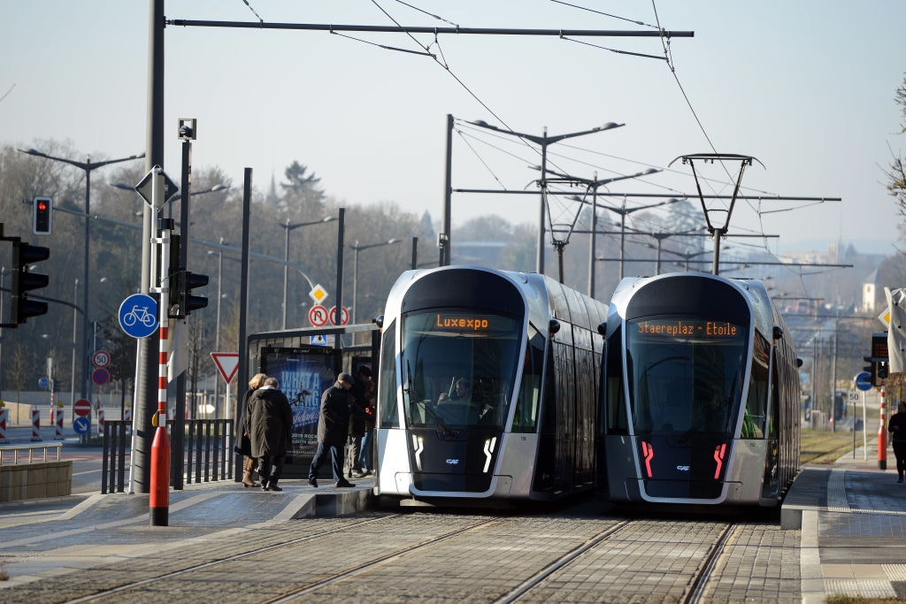 Two trams wait side by side at a station in Luxembourg