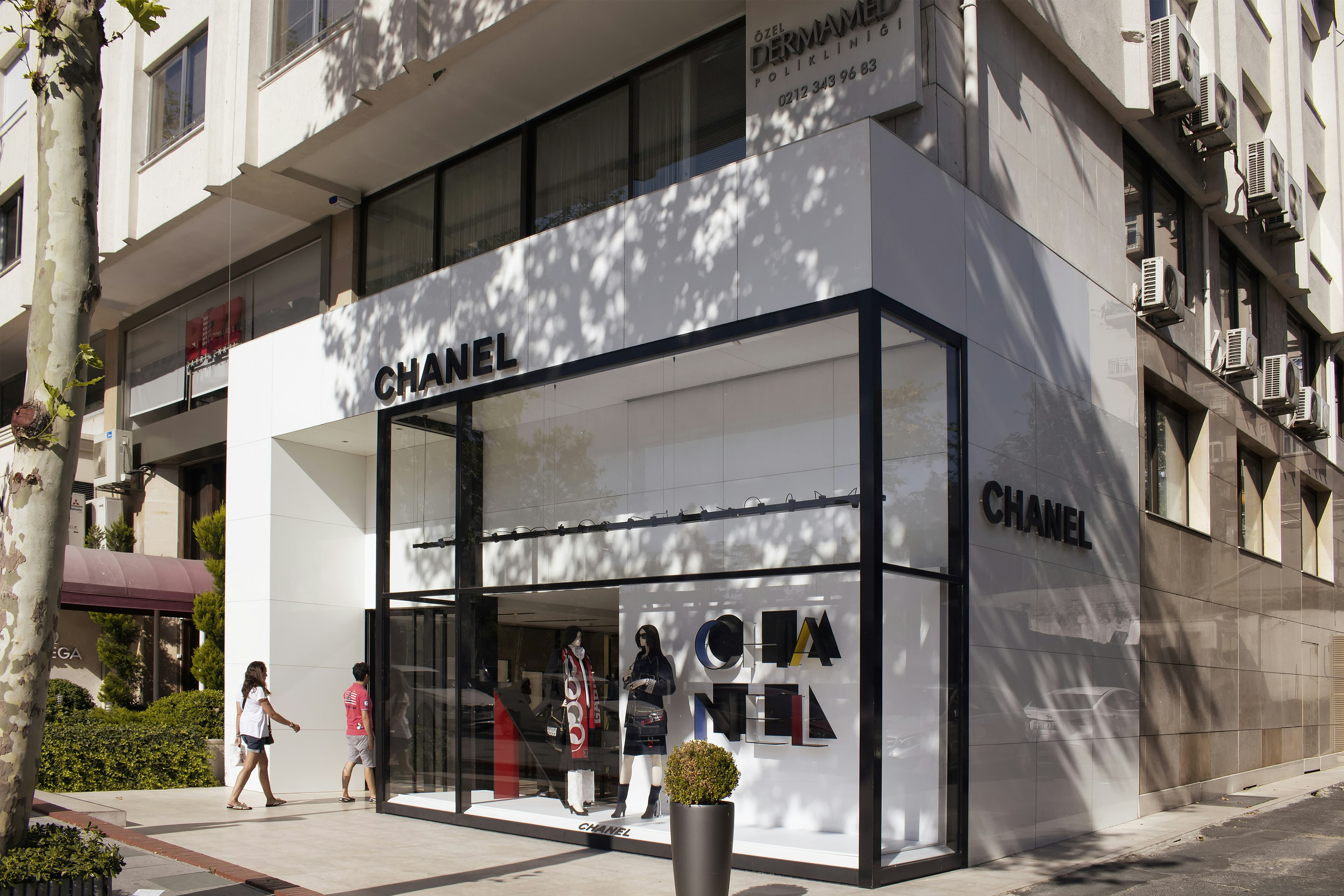 Two people are walking in to a Chanel store in the upmarket district of Nişantaşı in Istanbul. The store has an elegant black and white facade.
