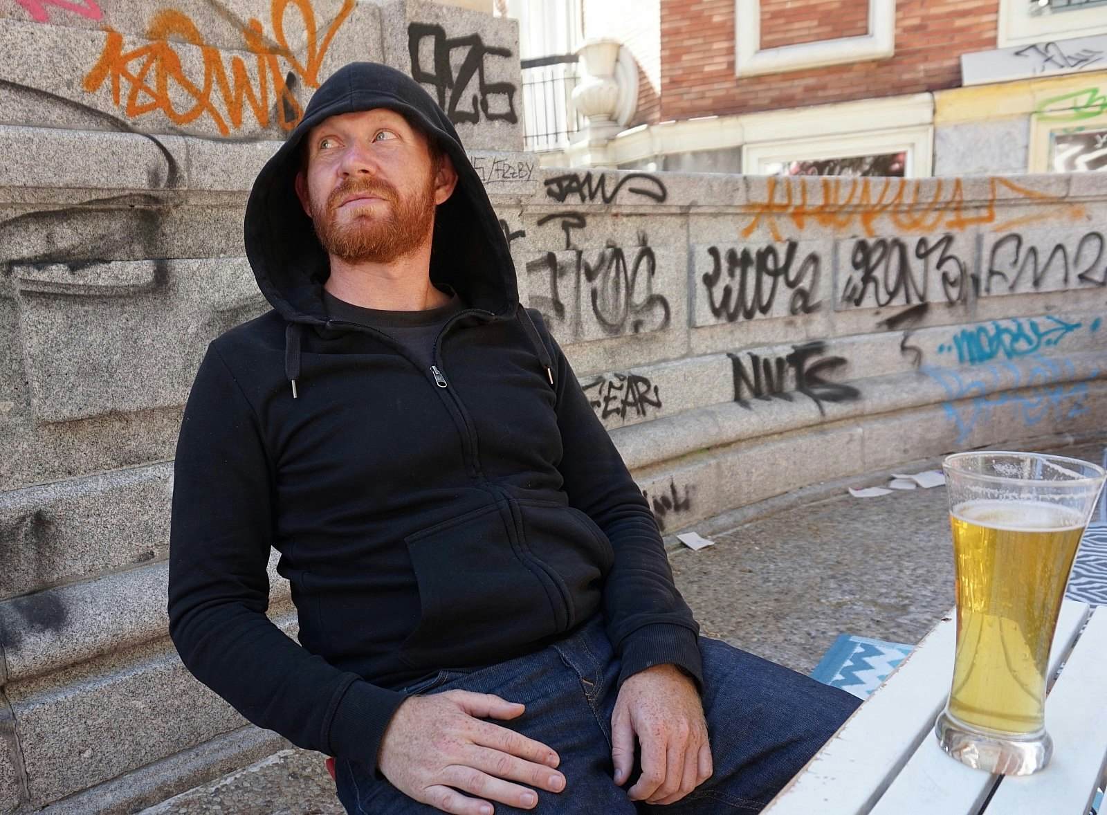 Daniel sits at an outdoor table with a pint of beer in Madrid, Spain