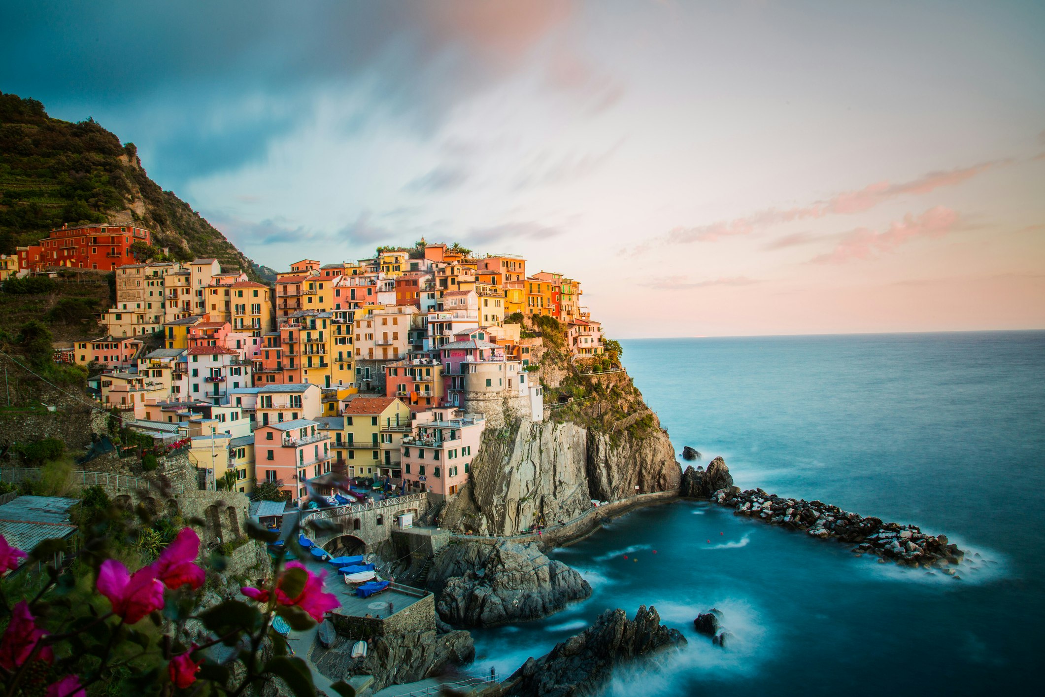 A shot of the town of Monterosso at dusk, lights shining over its coloured houses
