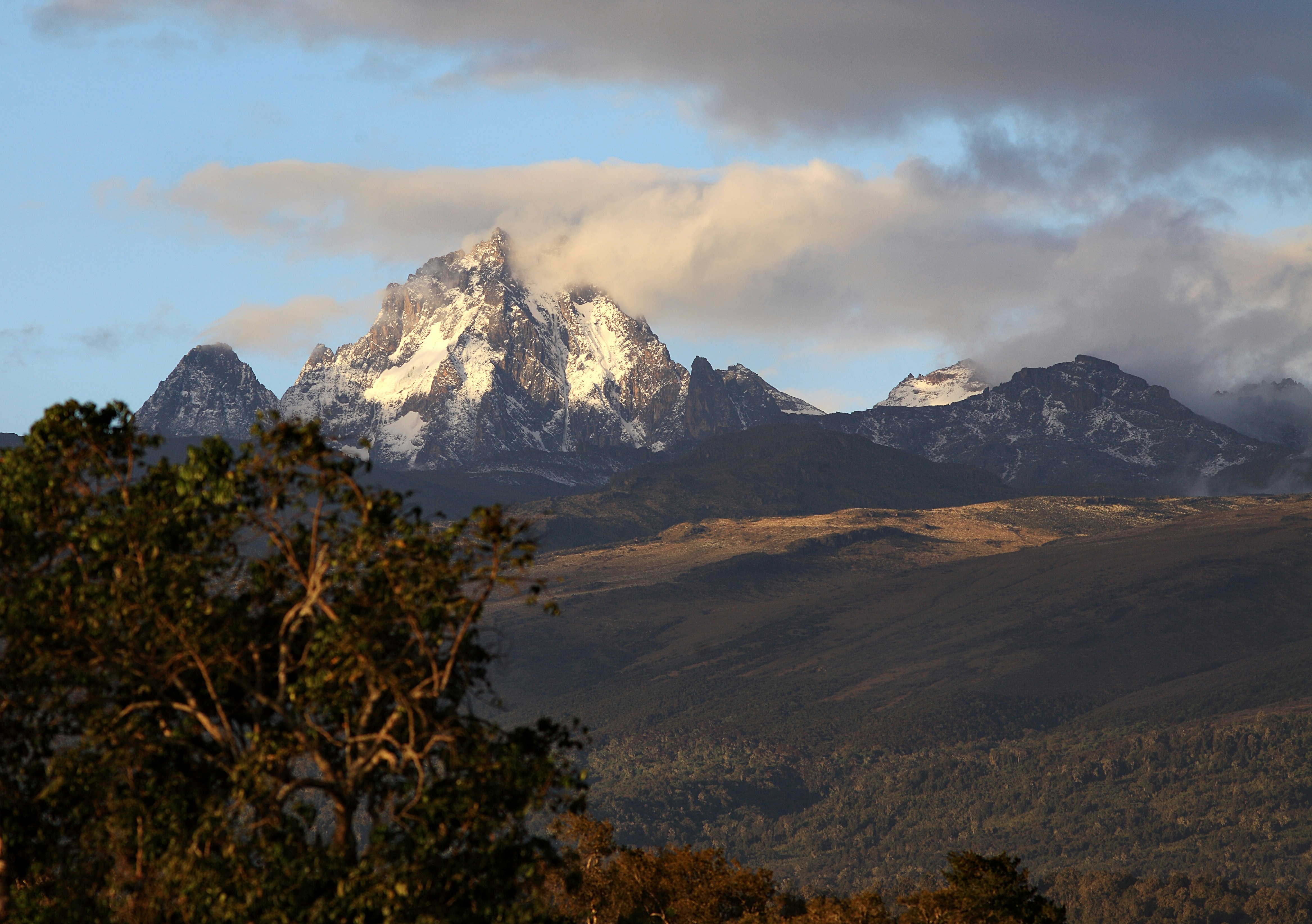 A man mountain bikes past the craggy peaks of Mount Kenya