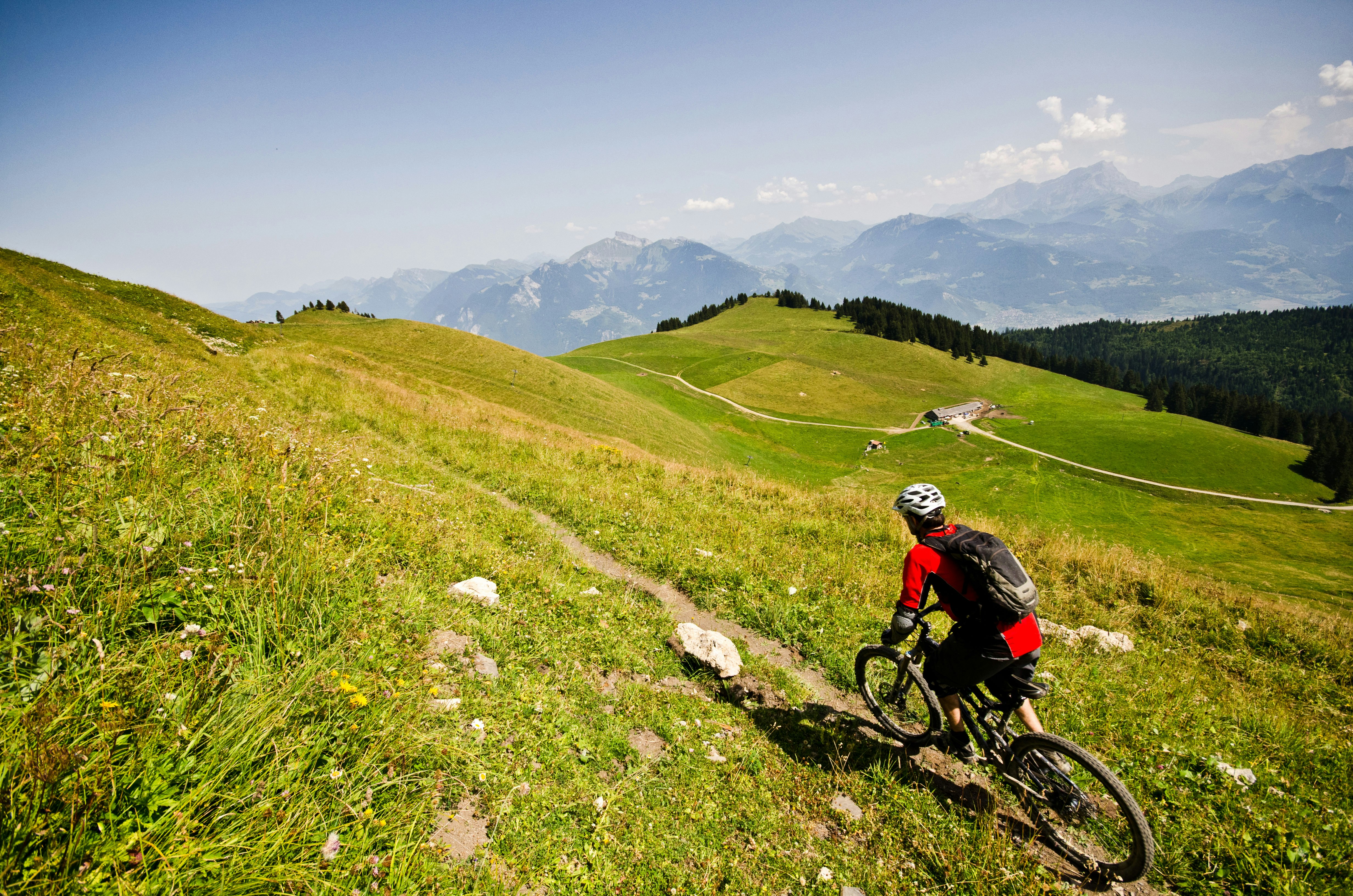 A mountain biker on a trail surrounded by green hillsides