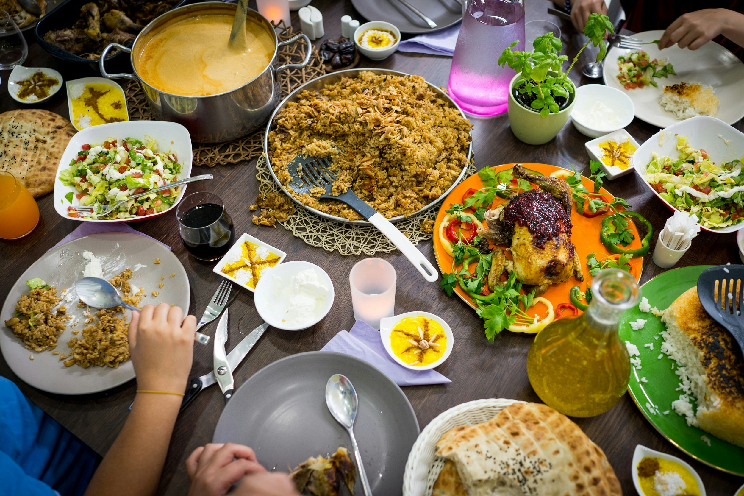 An aerial view of a table covered with different dishes, including rice, a curry dish, roasted chicken and a salad