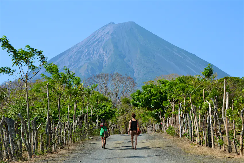 nicaragua.jpg Two people walk down a tree-lined road towards a volcano.