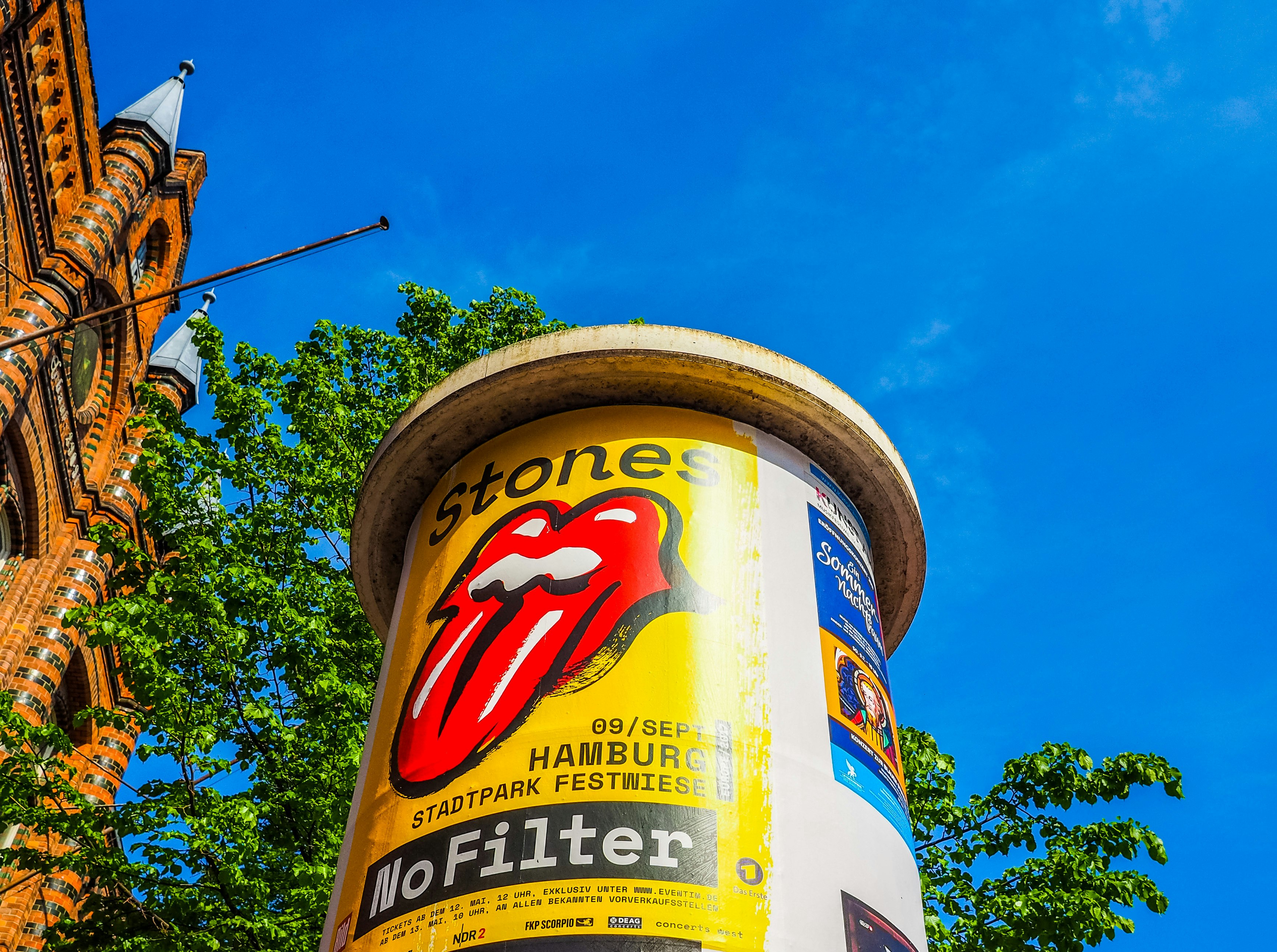 A water tower is emblazoned with a brightly colored tour poster for the Rolling Stones No Filter reunion