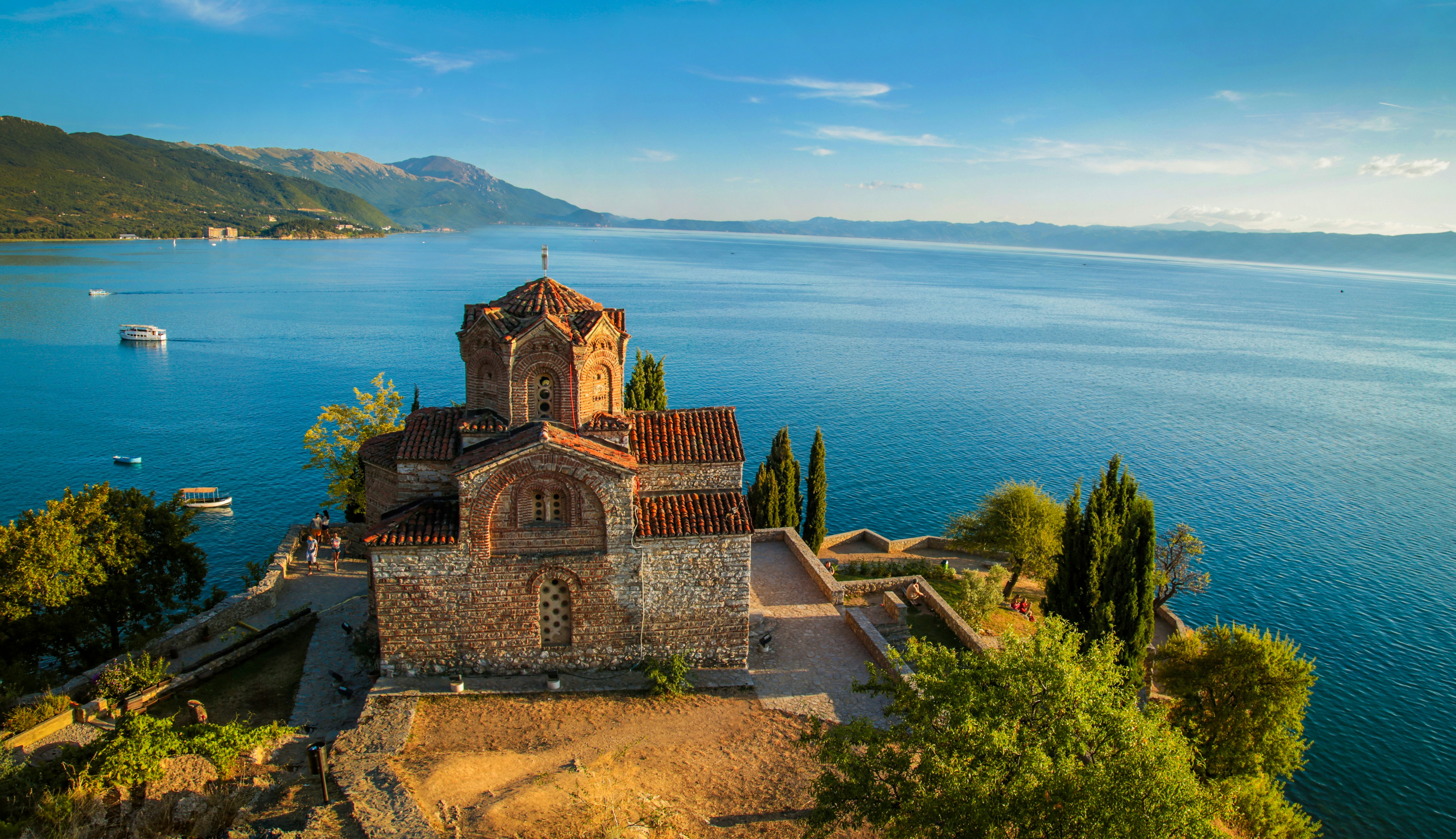 A Macedonian church stands on the side of a beautiful blue lake.