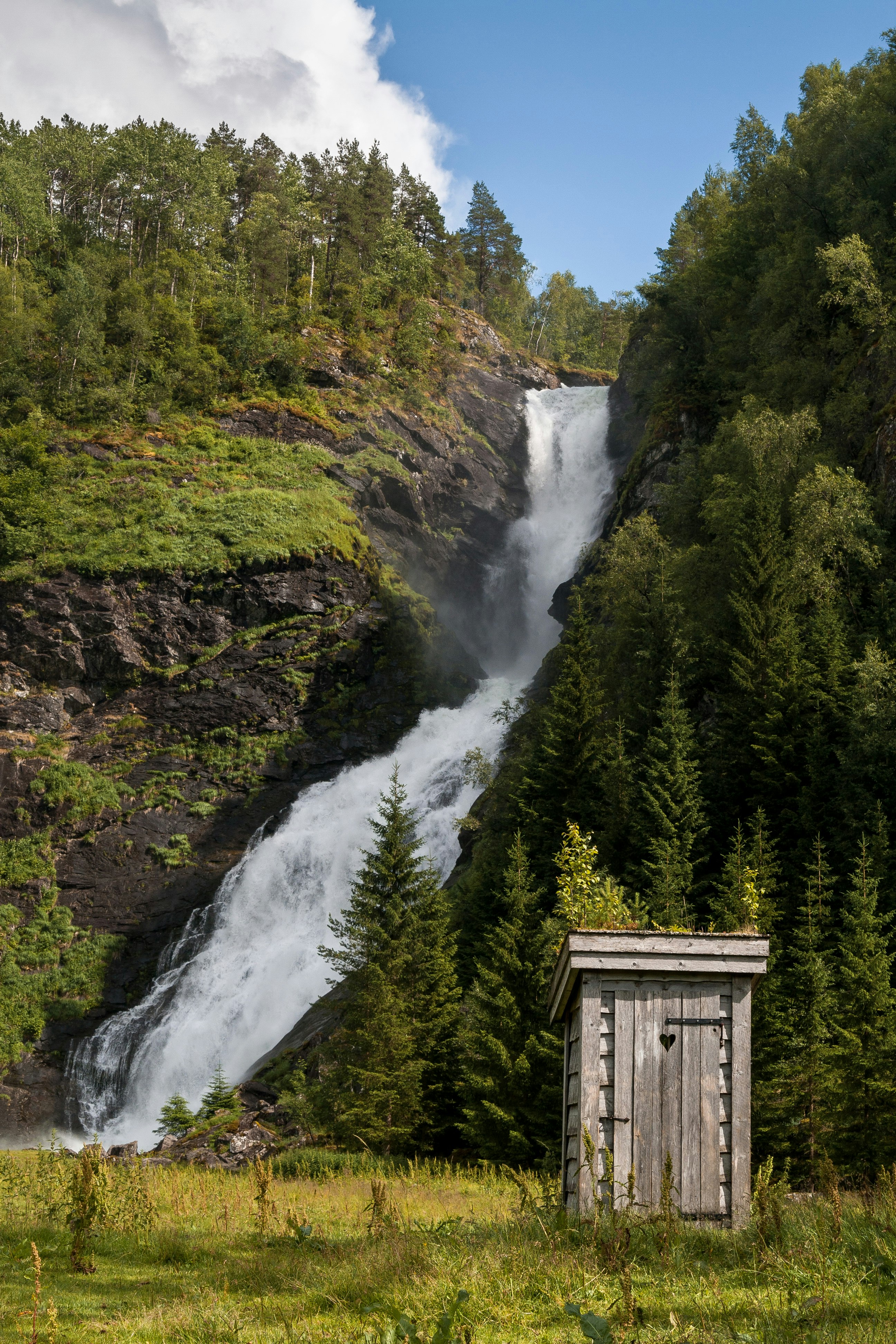 An outhouse next to a waterfall