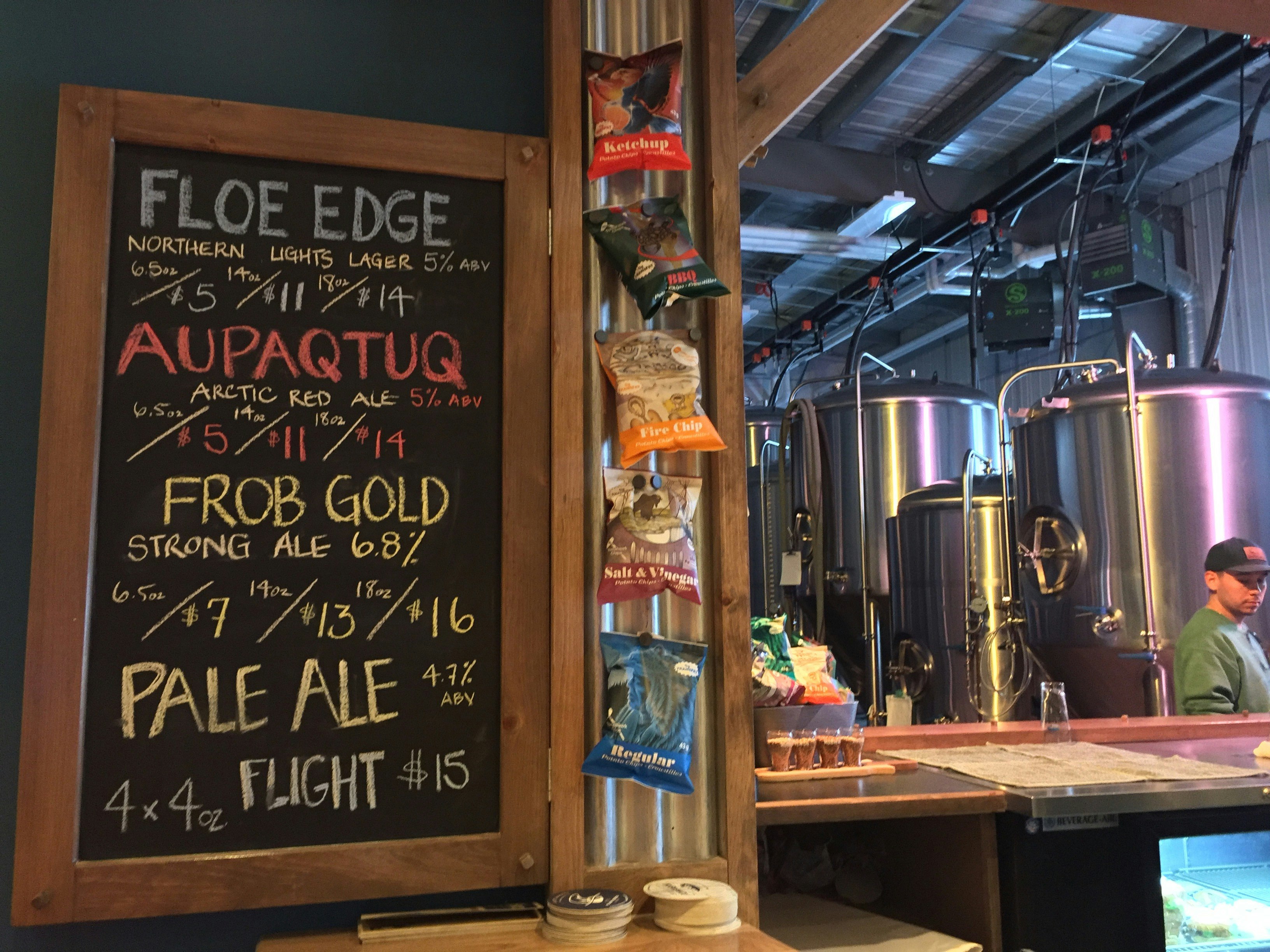 Inside the Nunavut Brewing Co microbrewery. Large polished-steel fermentation tanks are in the background, while a chalkboard beside the bar lists the various brews on offer.