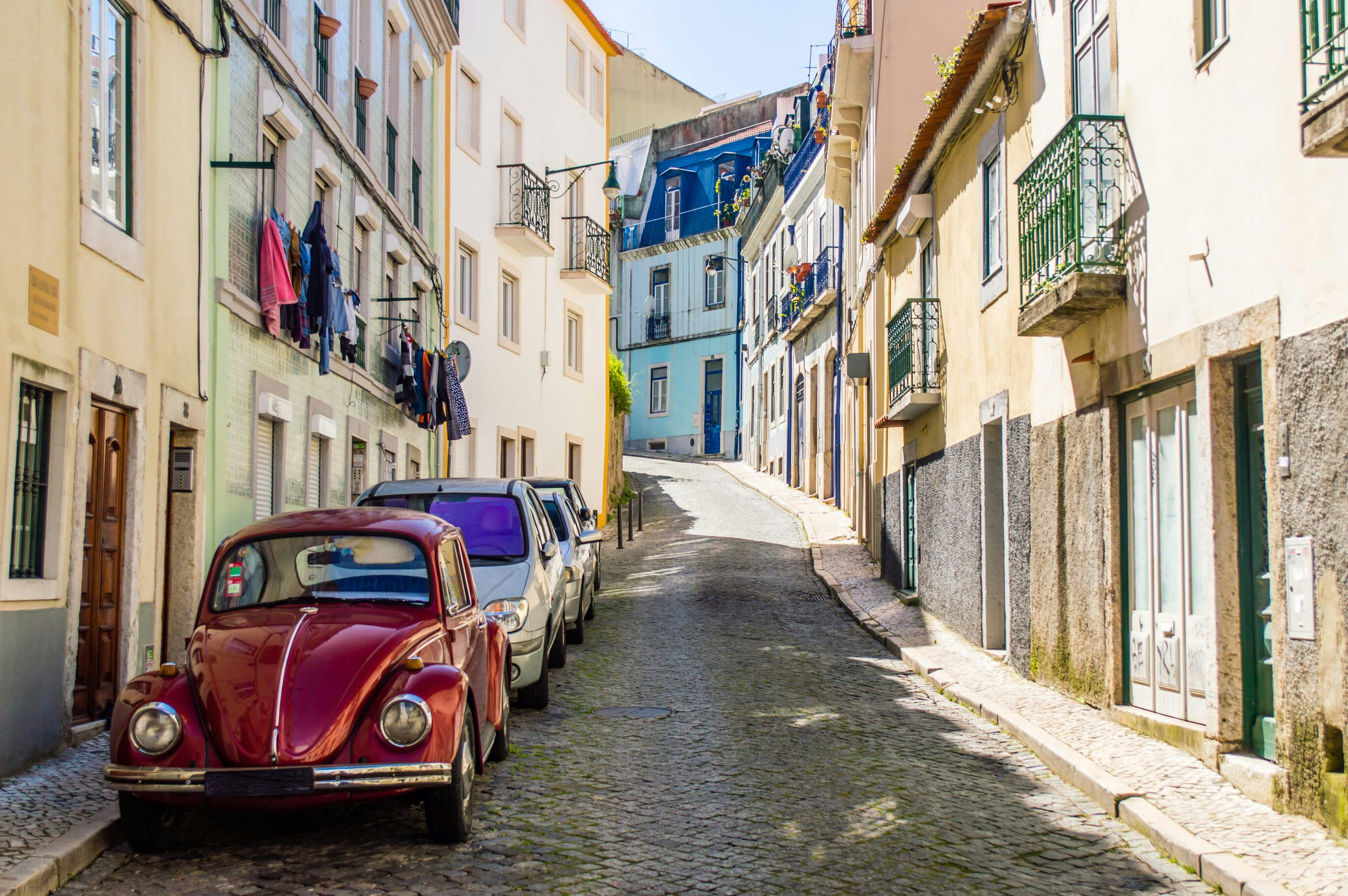 Cobblestoned winding street with old classic vintage beetle car in Lisbon