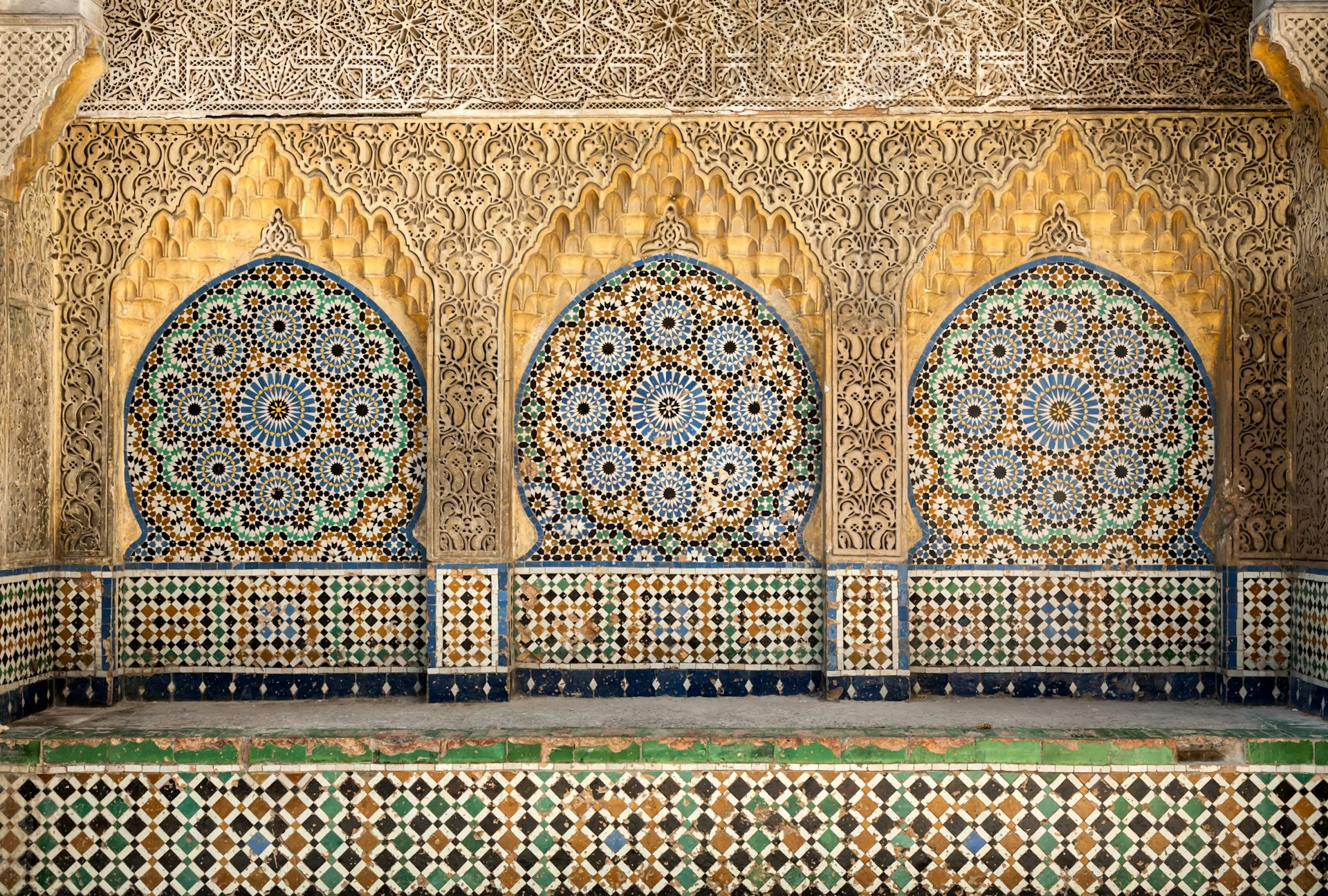 An alcove in the Kasbah, Tangier, tiled with ornate blue and yellow tiles and decorated with carved stone.