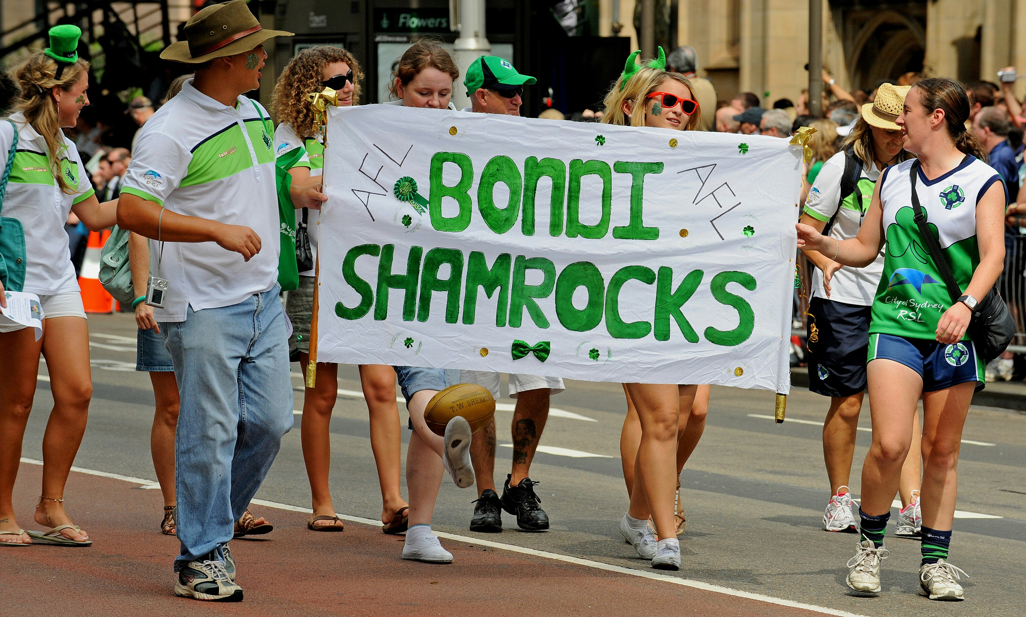 People in shorts and T-shirts hold up a banner saying 'Bondi Shamrocks' in a St Patrick's Day parade