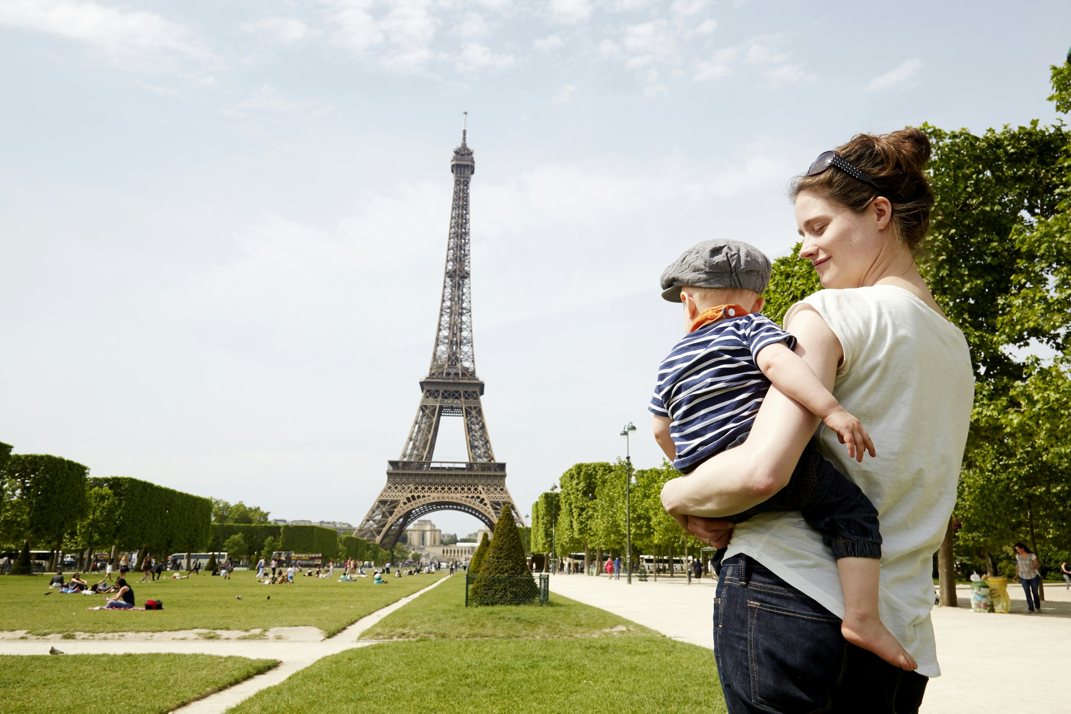 A mother holds a toddler on her hip as they stare at the Eiffel Tower together