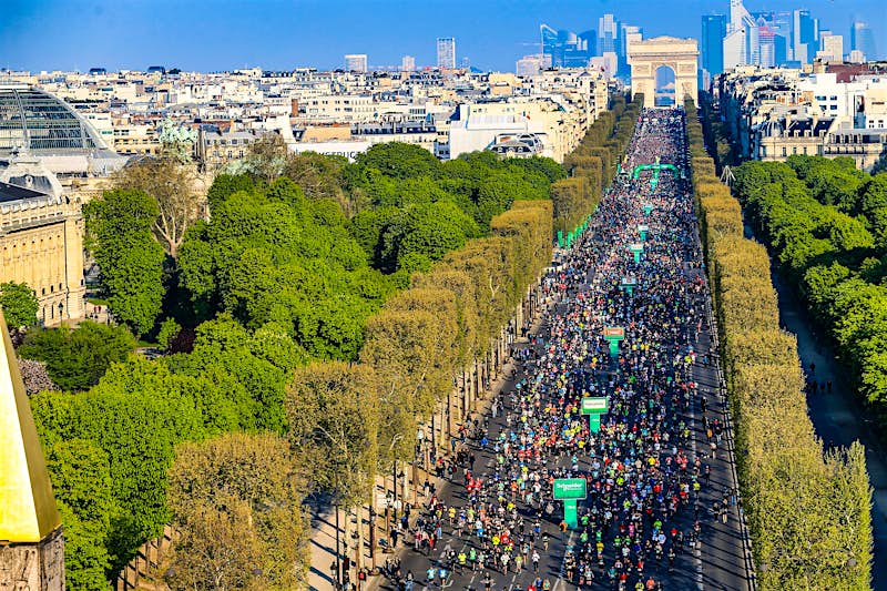 Under a cloudless sky tens of thousands of runners make their way from the Arc de Triomphe down the tree-lined Champs-Élysées.