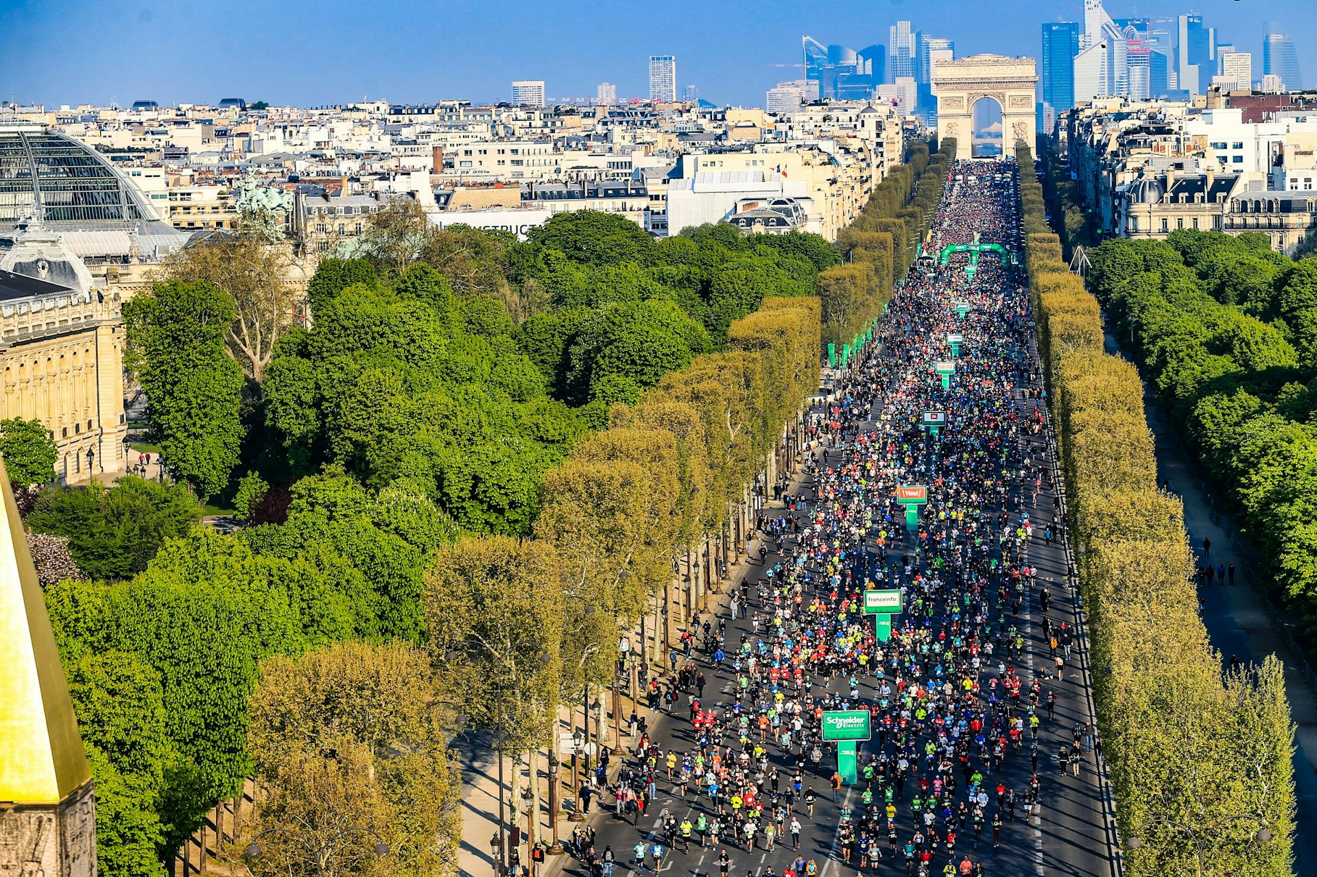 Under a cloudless sky tens of thousands of runners make their way from the Arc de Triomphe down the tree-lined Champs-Élysées.