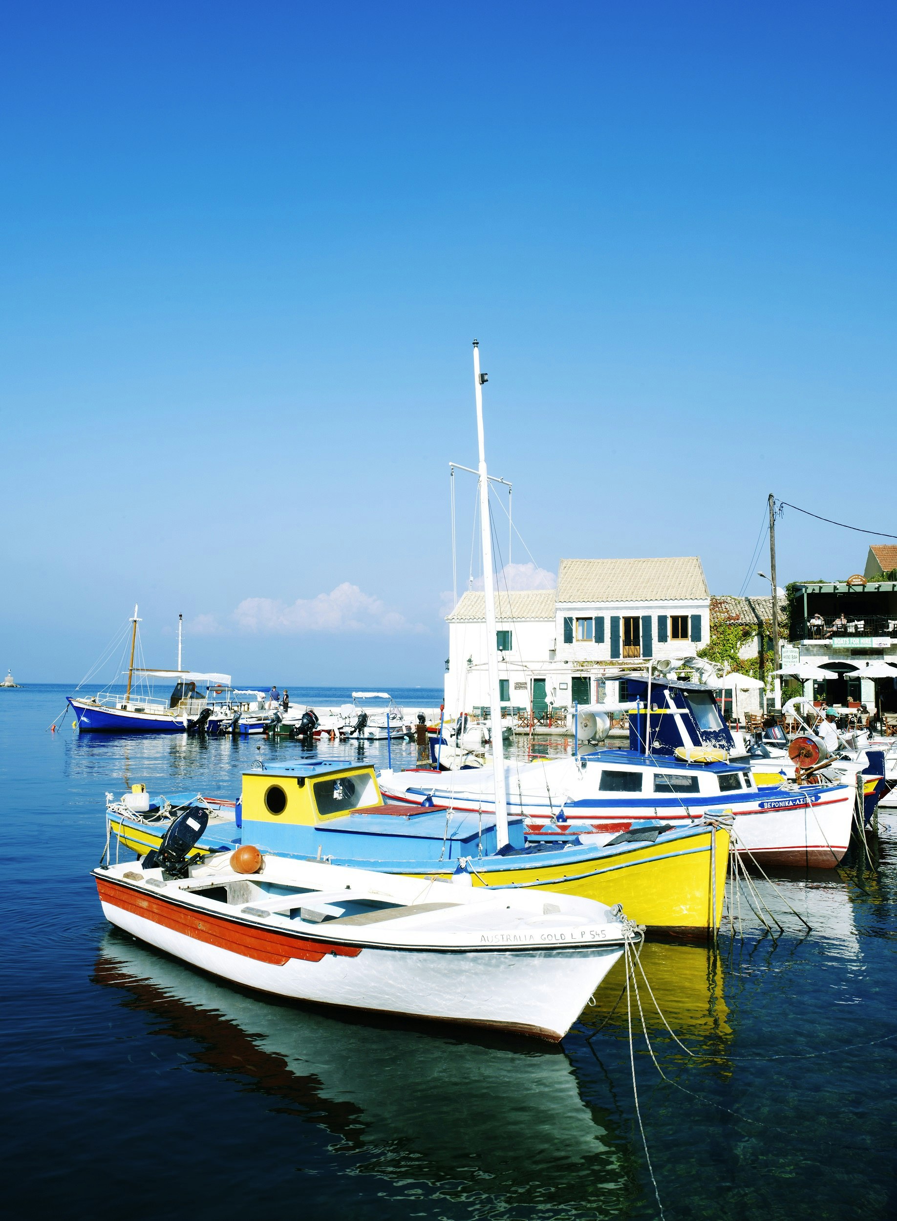 Several brightly coloured fishing boats are docked together in a small harbour. 