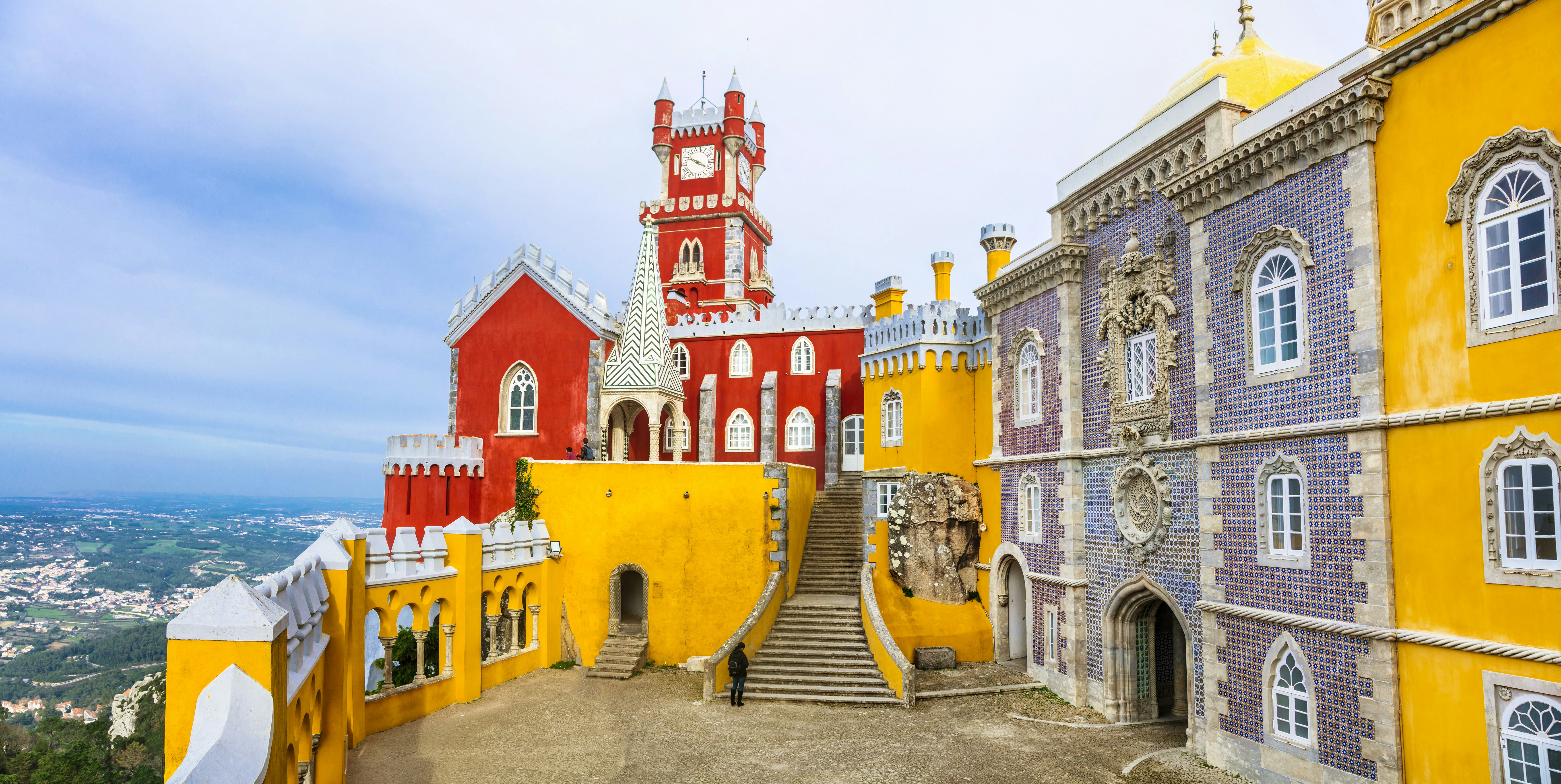 Exteriör av Palácio Nacional da Pena (Pena National Palace) i Sintra;  dess väggar är målade ljust gula och orange.