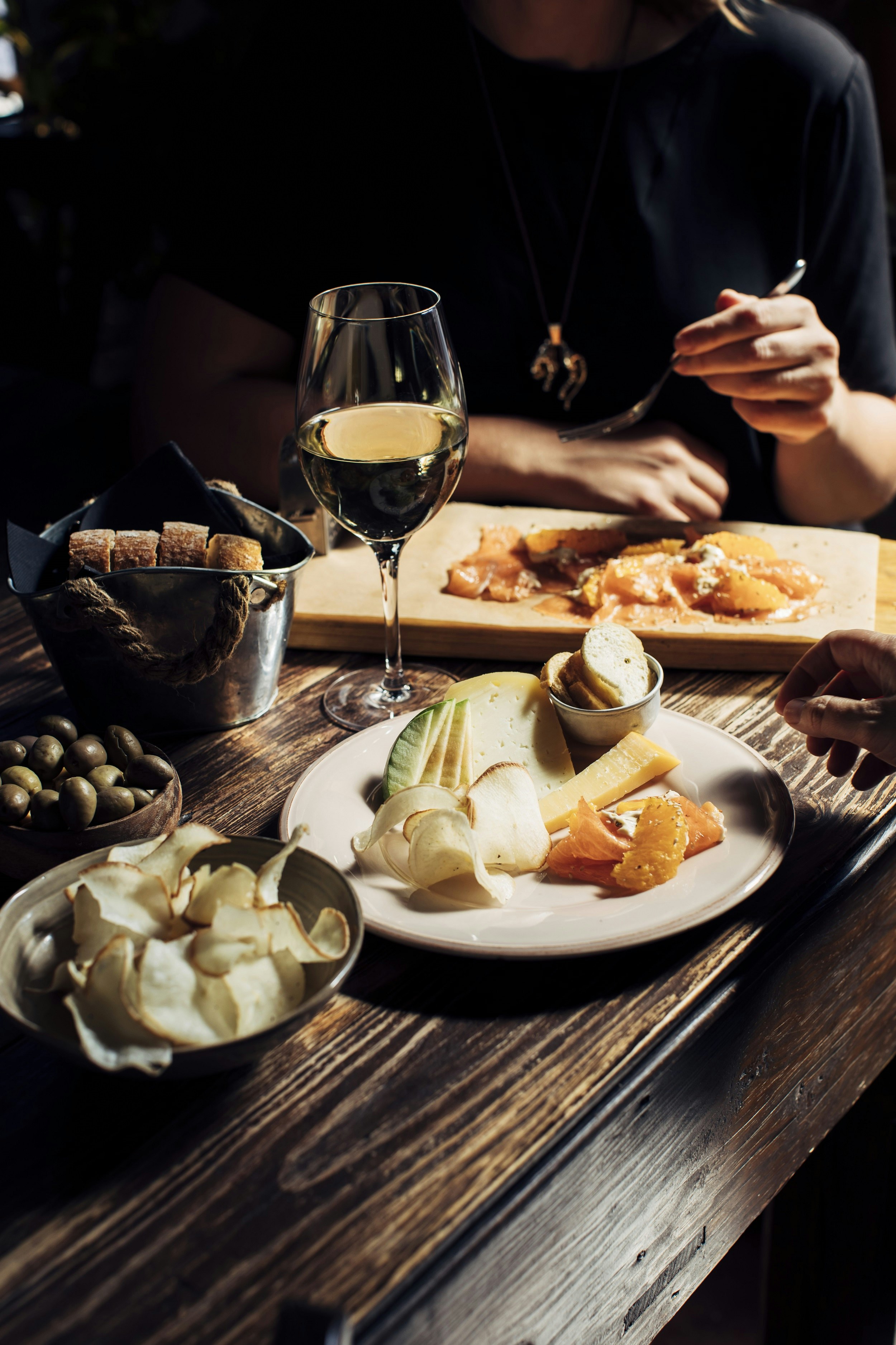 A dark-wood table is dotted with plates of petiscos (small eats), ranging from olives to homemade crisps, and tiny tins holding slices of fresh bread.