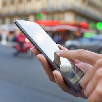 closeup of a woman's hand using her smart phone on the street
