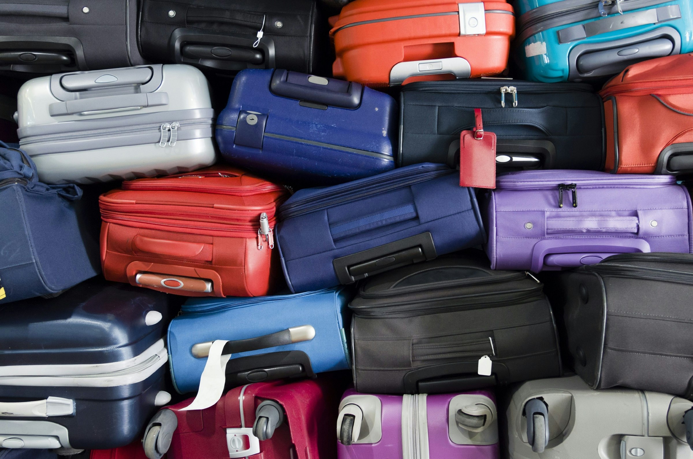 A pile of different coloured suitcases stacked on top of each other. 