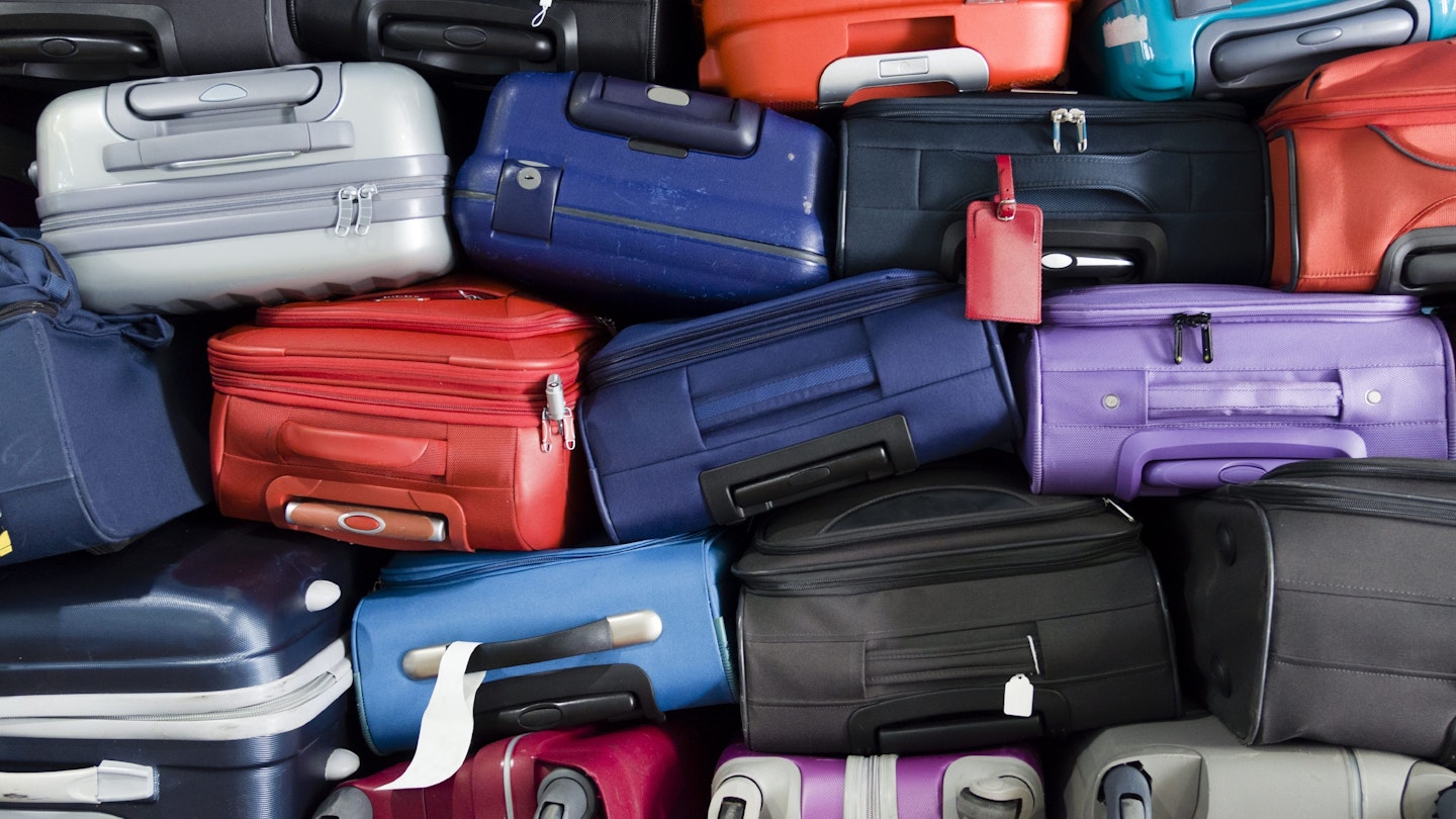 A pile of different coloured suitcases stacked on top of each other