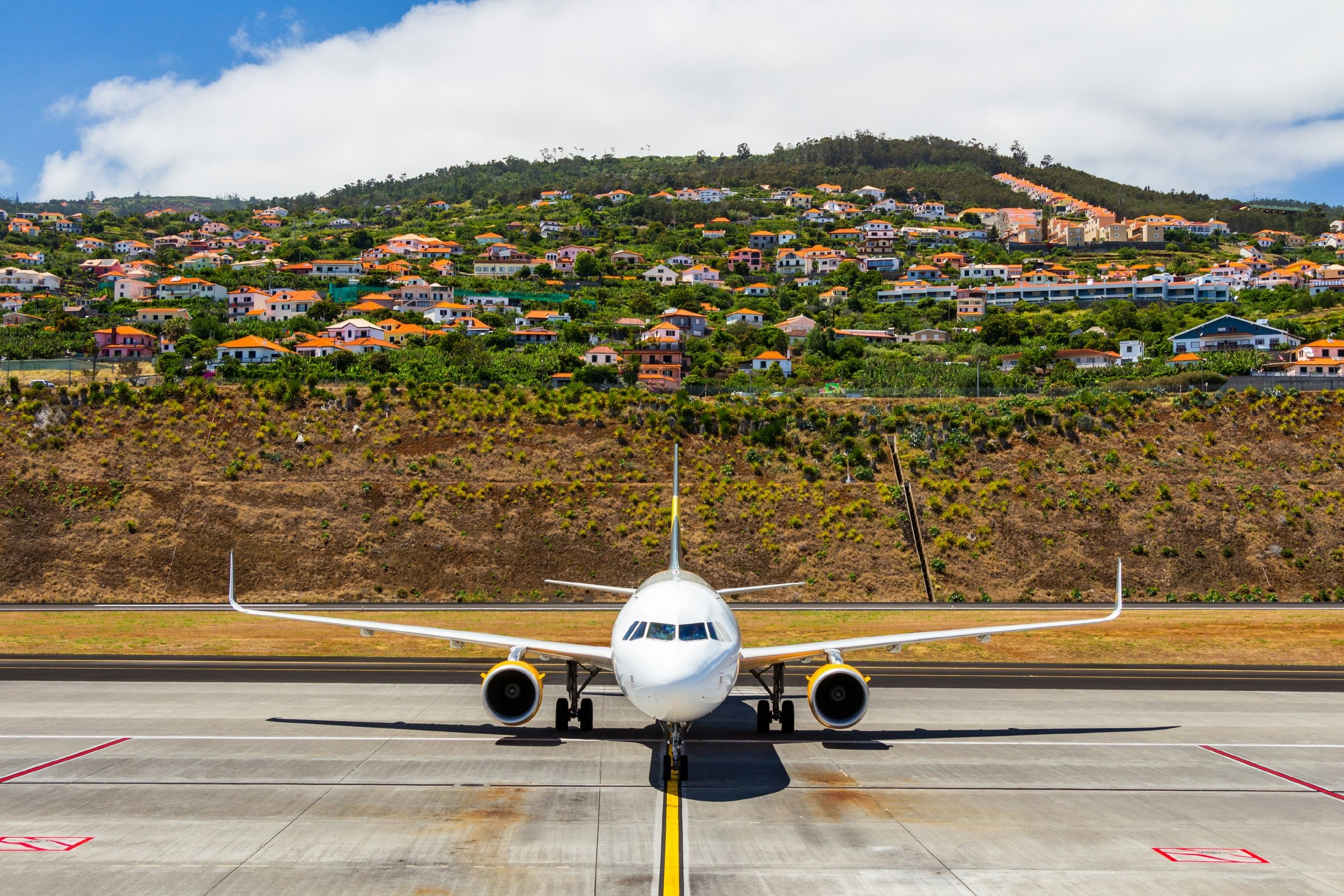 Passenger jet on the airport tarmac with Agua de Pena village in the background in Madeira, Portugal
