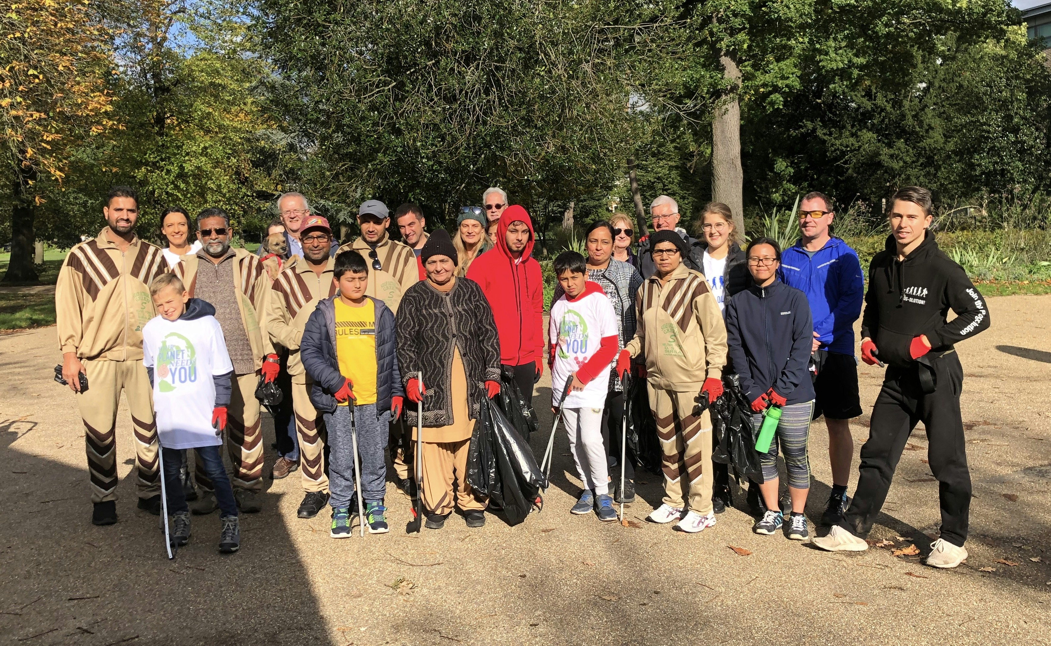 The group of people who took part in the plogging class stand together for a photograph. Some hold black bags and litter pickers.