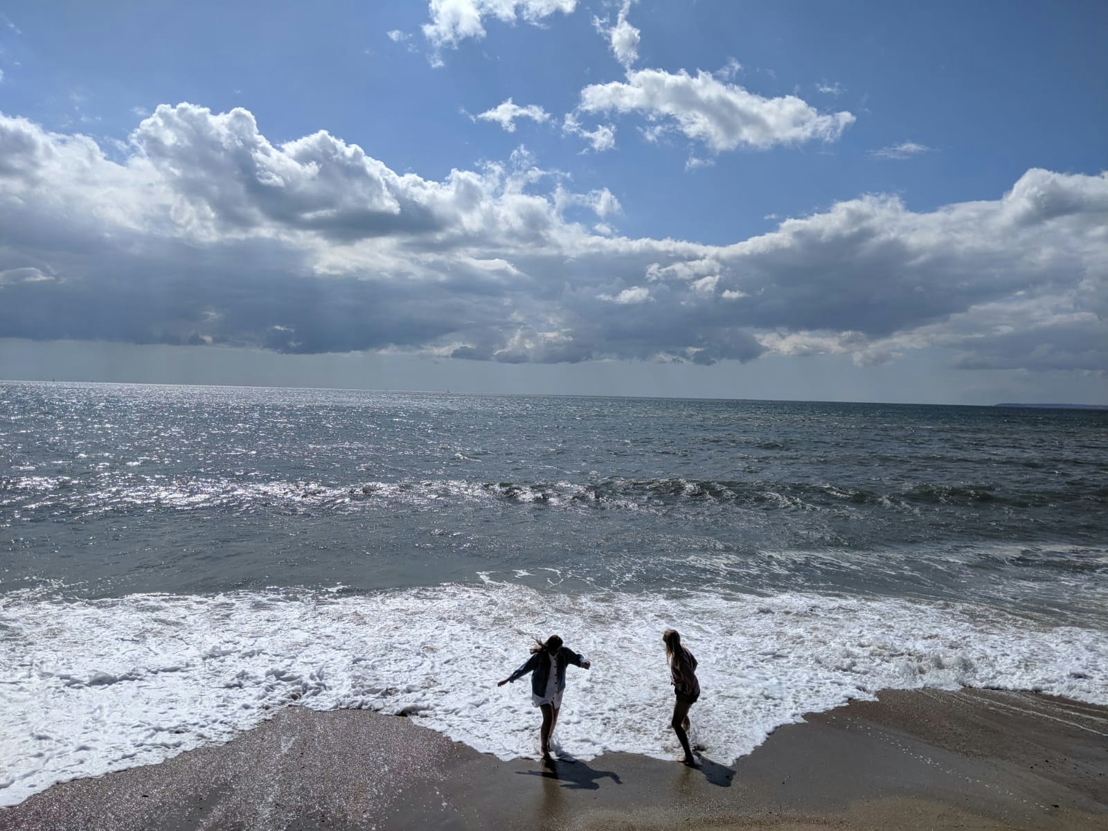 Two people play in the surf on a beach at a distance; New Forest spending diary