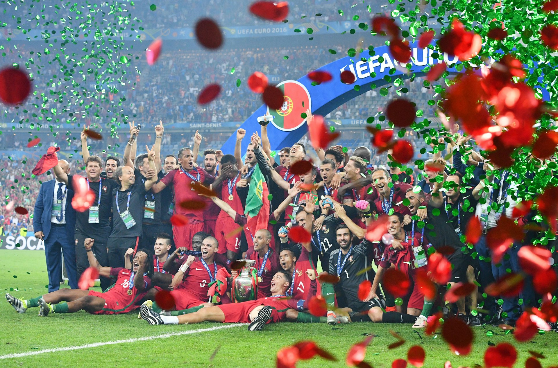The Portuguese team posing for a celebratory photo on on the pitch amidst red and green confetti after winning the European Championships in 2016. 