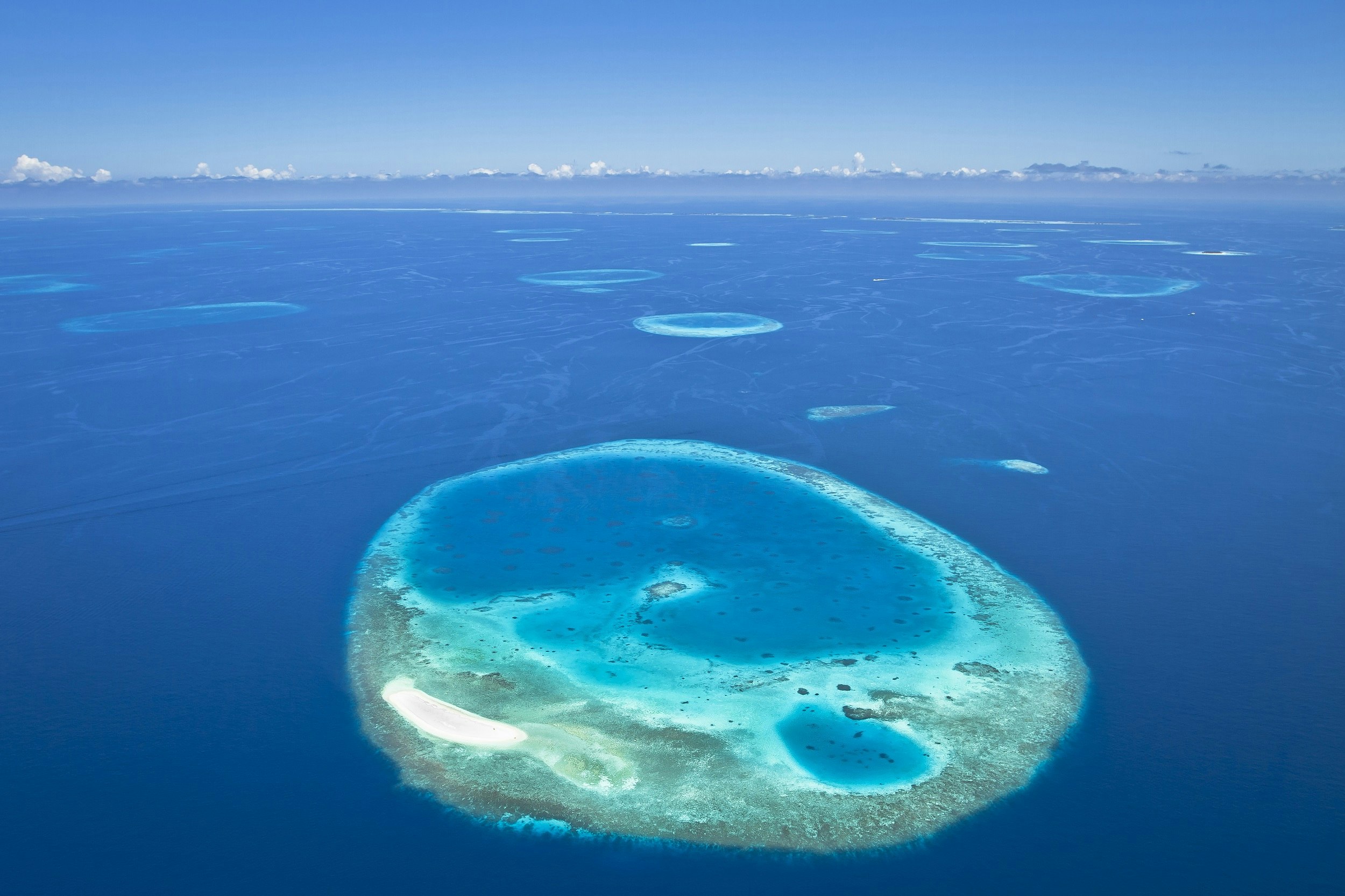 Aerial shot of several shallow reefs in turquoise water.