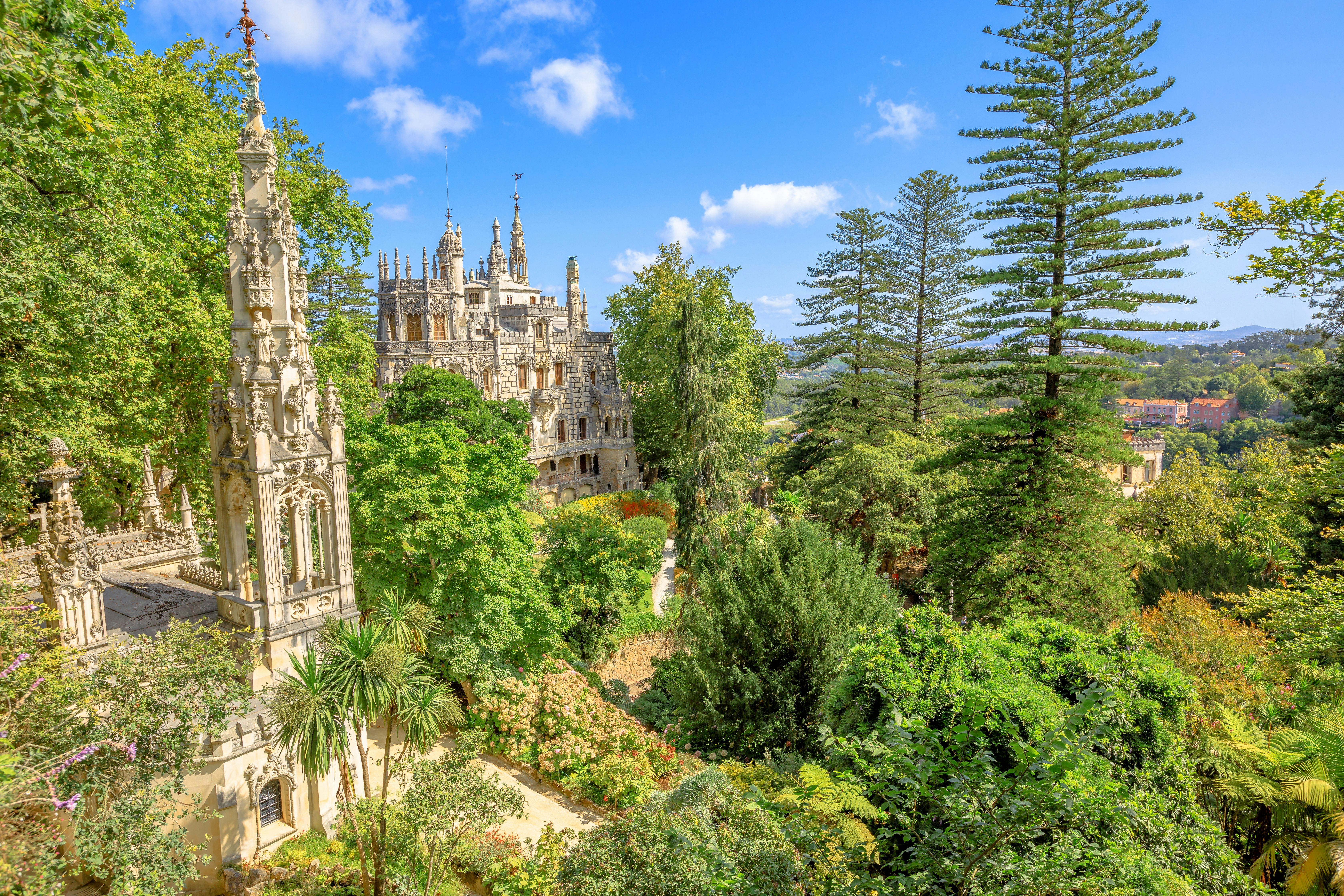 The spires of Quinta da Regaleira are visible through the trees from an elevated viewpoint.