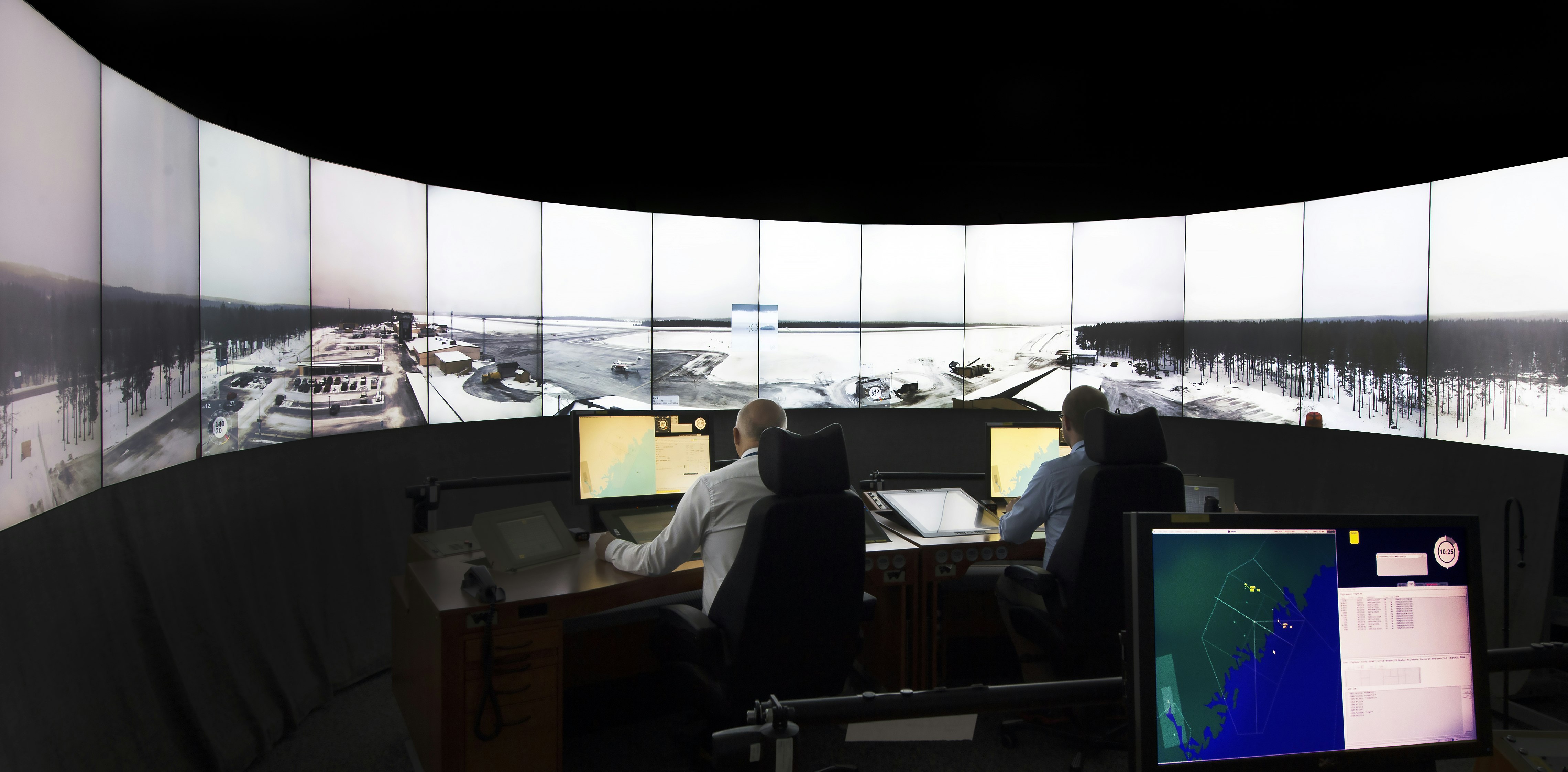 A digital airport control tower with a wall of screens showing air traffic