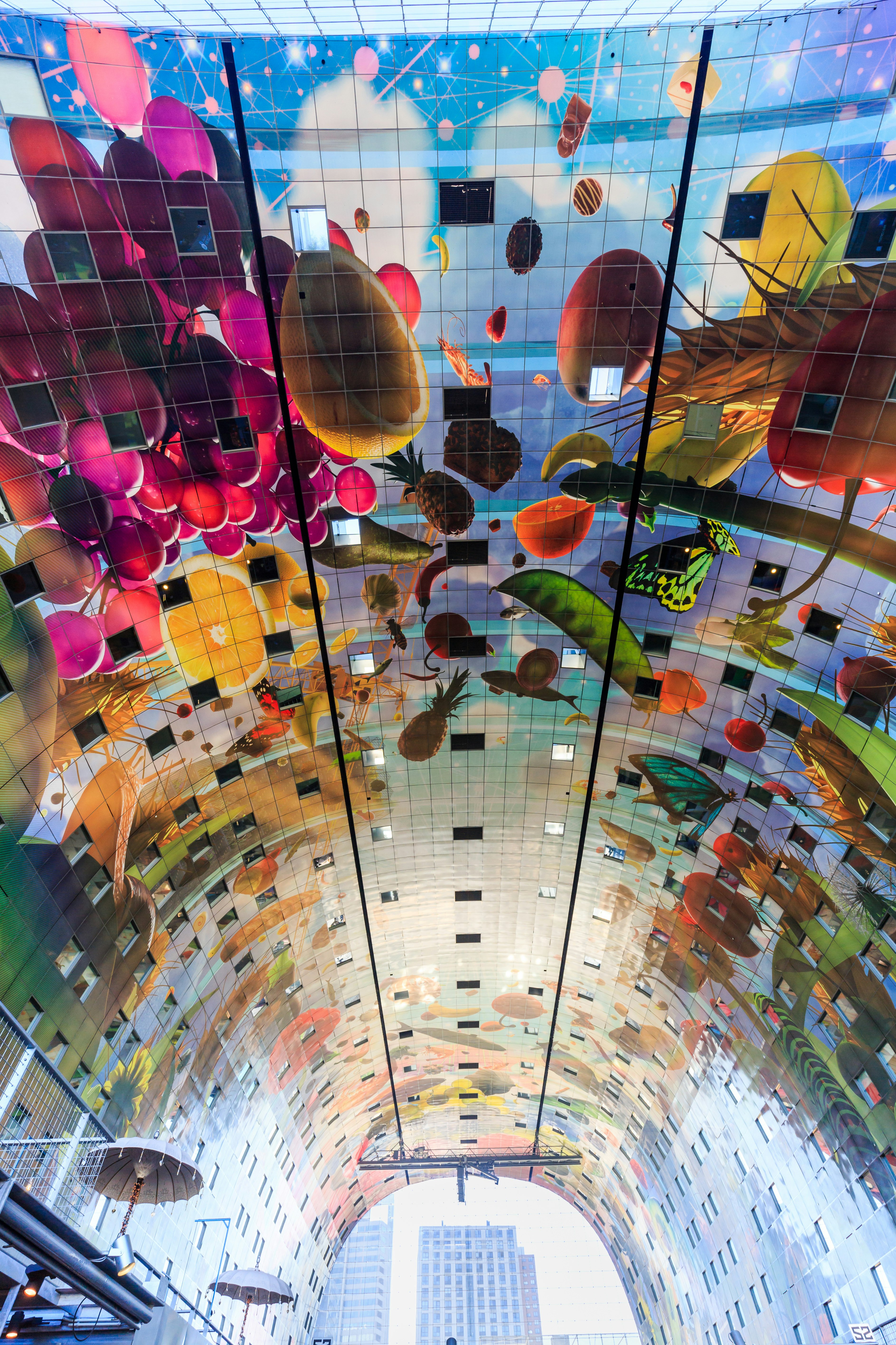The huge arched ceiling of the Rotterdam Markthal; it's entirely covered with a projection of a colourful artwork.