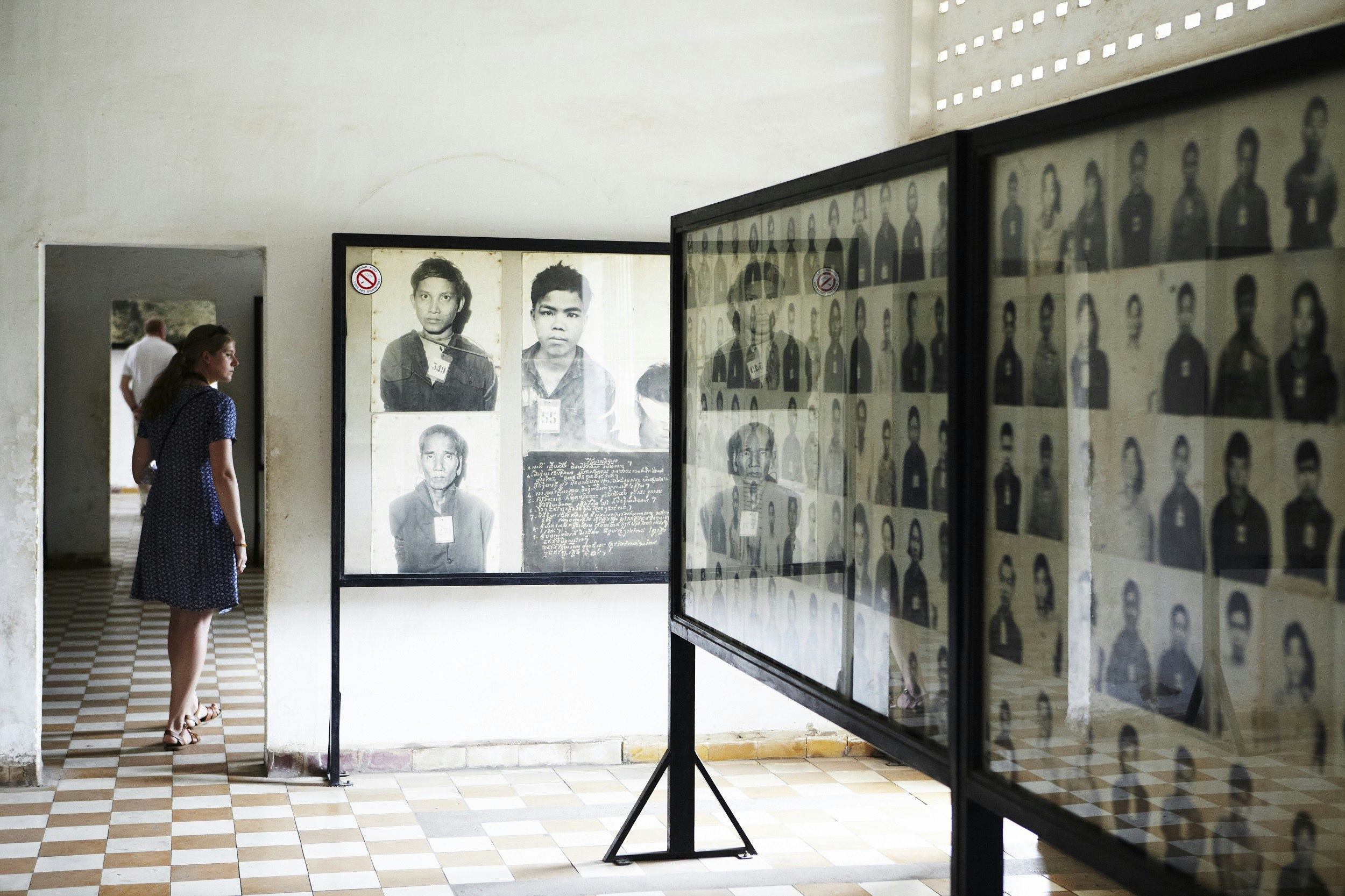 A room with walls and a central display covered with black-and-white head shots of people.