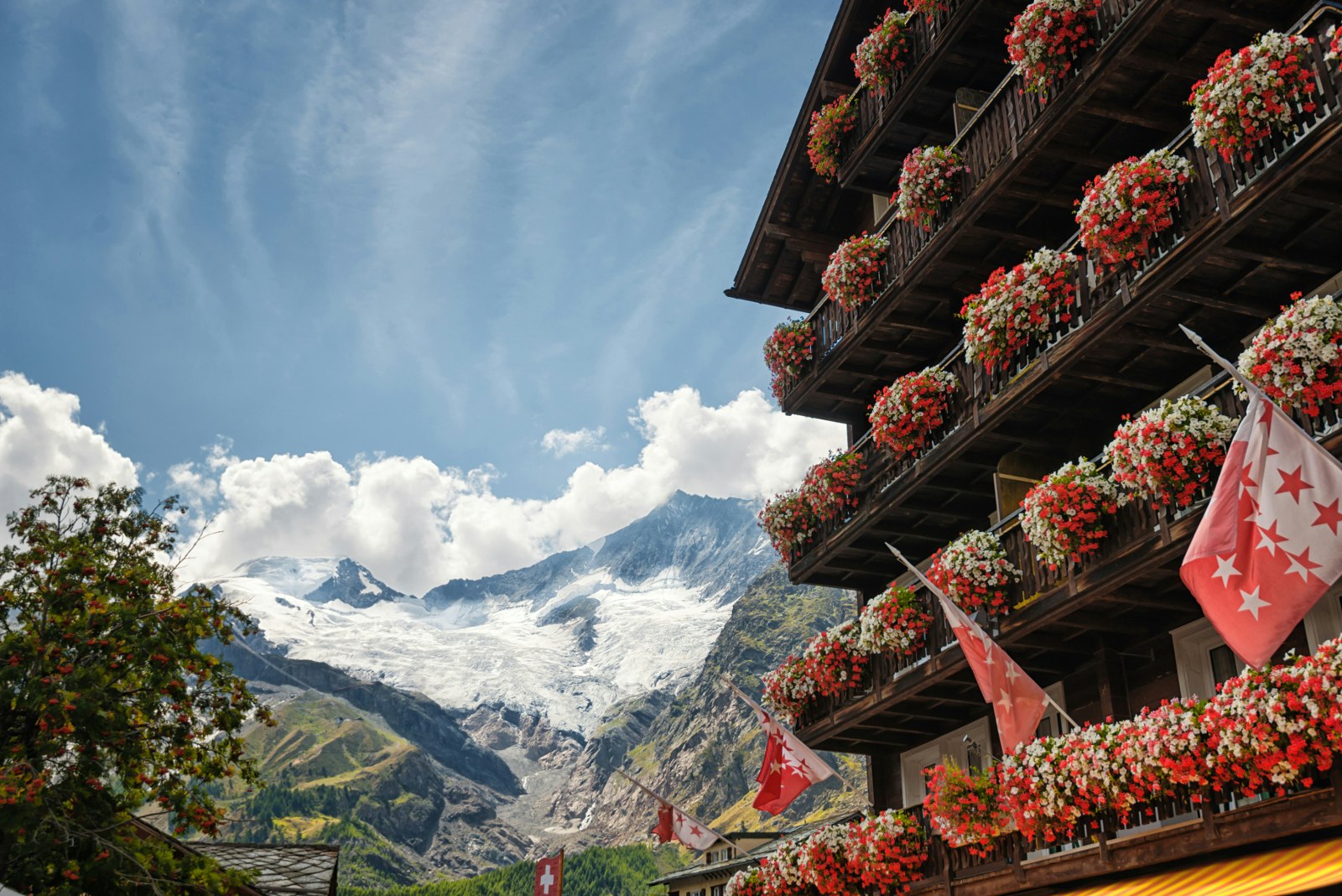A flower-covered chalet at Saas Fee, with glacier-covered slopes above
