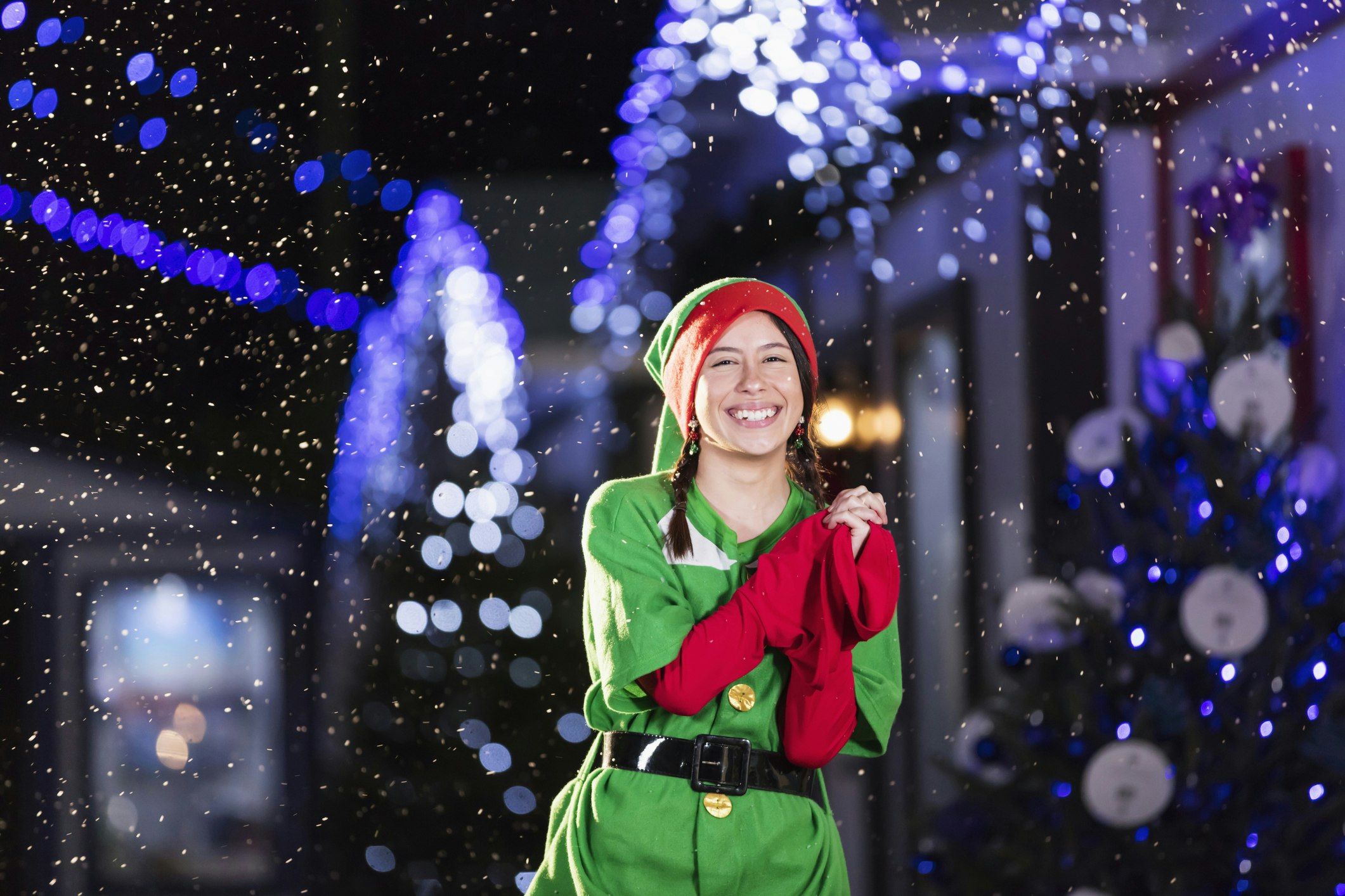 A picture of a girl dressed as one of Santa's elves with twinkling lights around her