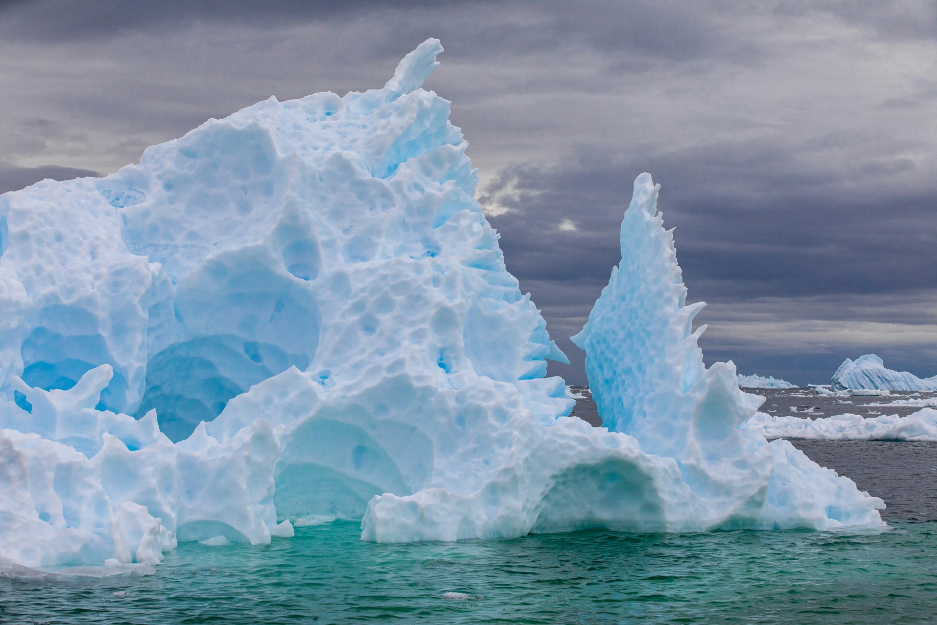 An iceberg of blue and white rises from the ocean.